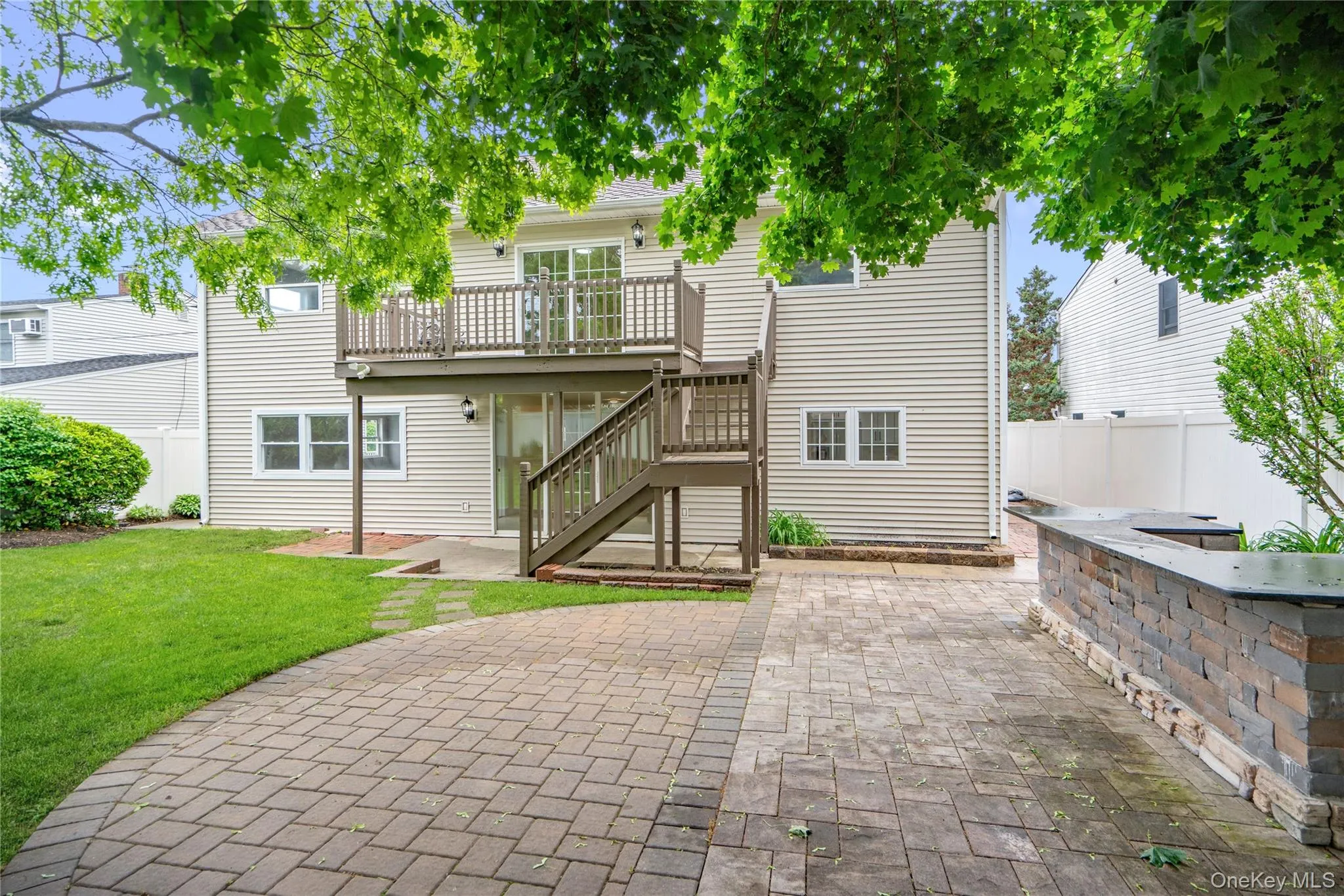 Expansive paver patio featuring a built-in stone veneer outdoor kitchen prep area Expansive paver patio featuring a built-in stone veneer outdoor kitchen prep area