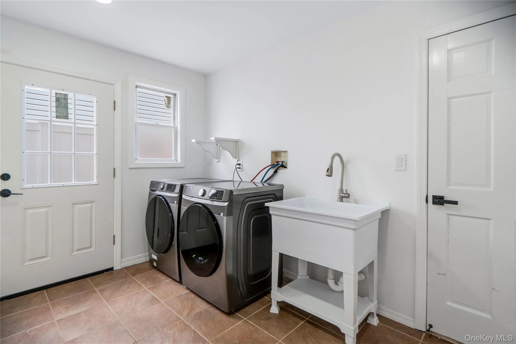 Dedicated laundry space featuring a utility sink and a side entrance door and window for natural light Dedicated laundry space featuring a utility sink and a side entrance door and window for natural light