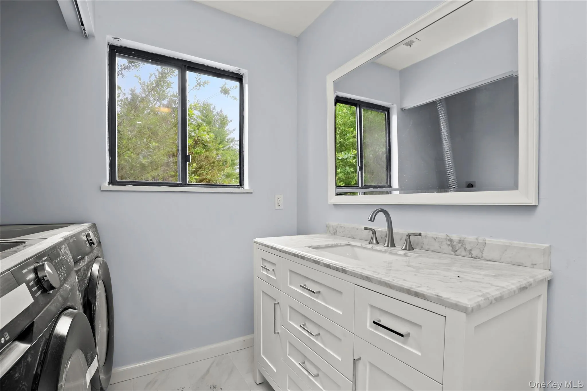 Laundry room with washer and dryer, baseboards, light marble finish floors, and plenty of natural light Laundry room with washer and dryer, baseboards, light marble finish floors, and plenty of natural light