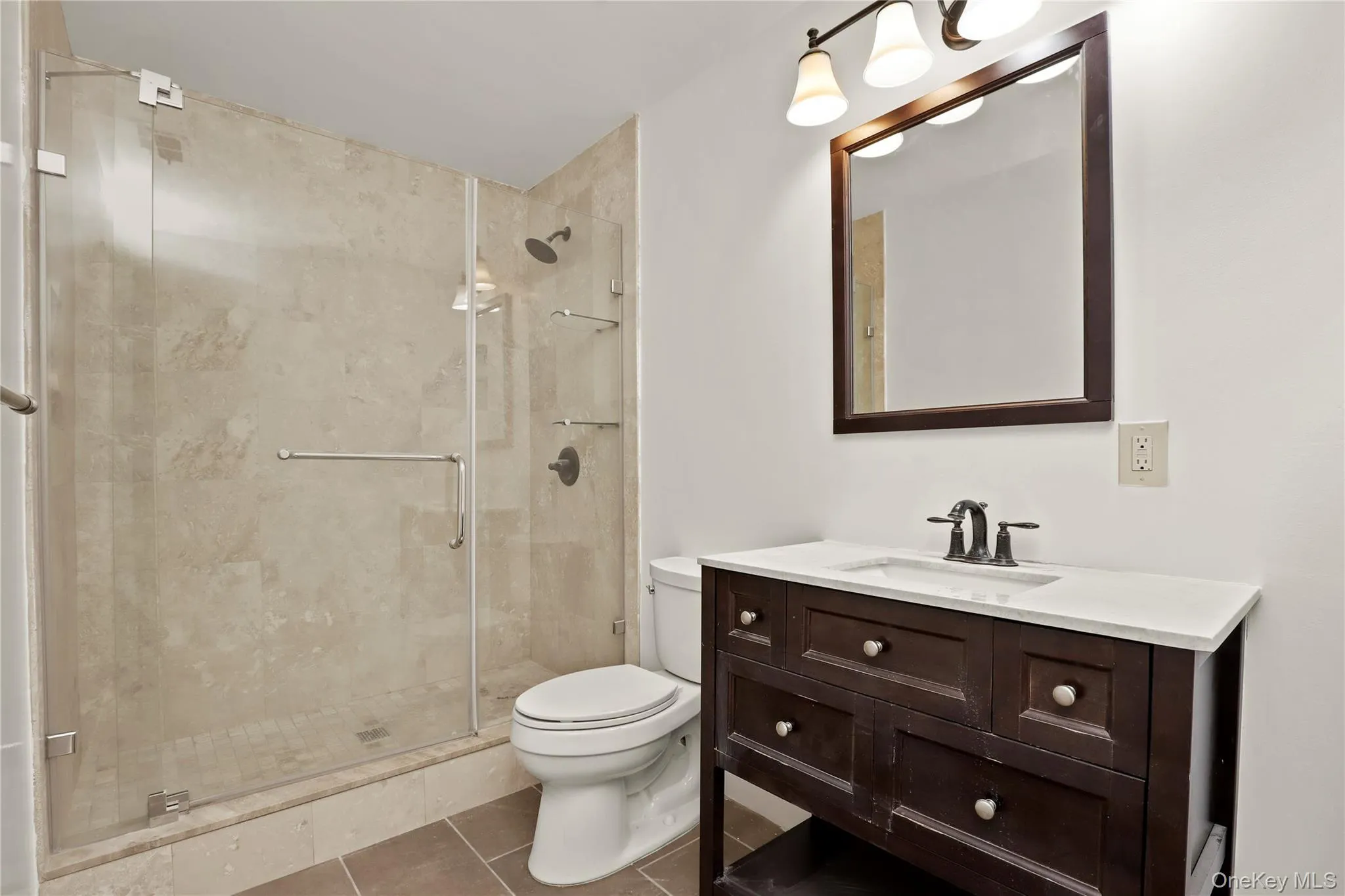 Full bathroom featuring toilet, a stall shower, vanity, and tile patterned floors Full bathroom featuring toilet, a stall shower, vanity, and tile patterned floors