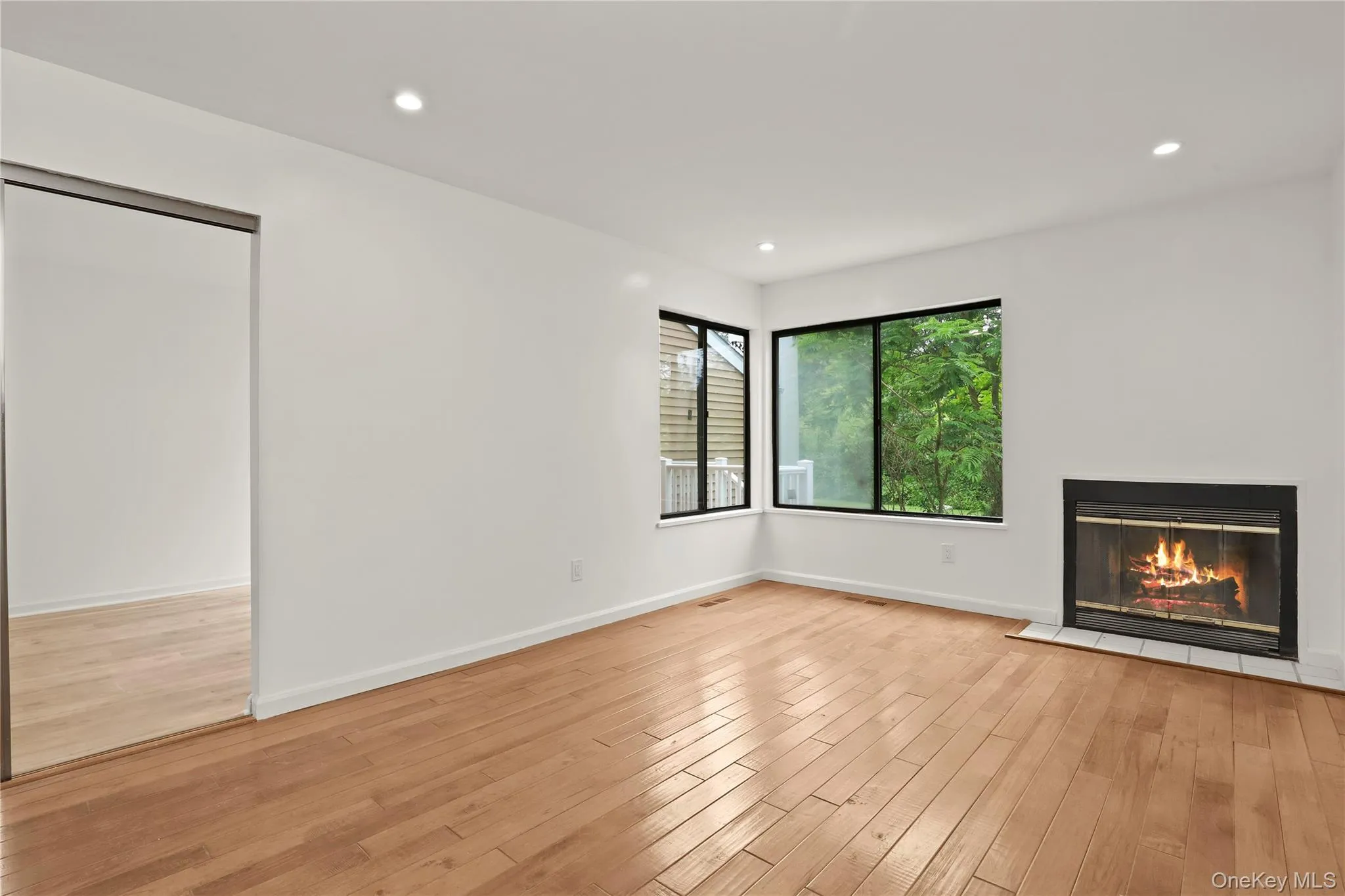 Unfurnished living room featuring light wood-type flooring, a glass covered fireplace, baseboards, and recessed lighting Unfurnished living room featuring light wood-type flooring, a glass covered fireplace, baseboards, and recessed lighting