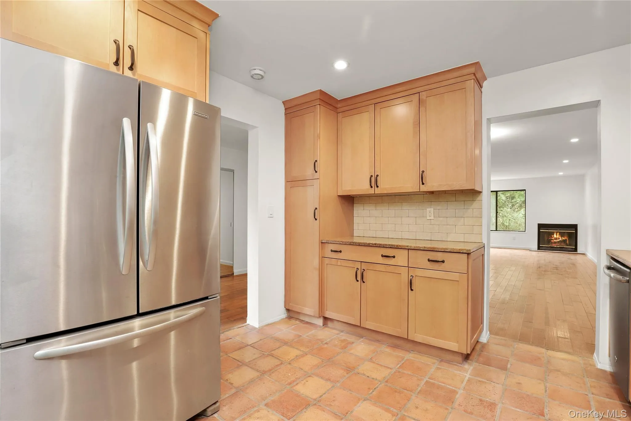 Kitchen with freestanding refrigerator, light brown cabinetry, tasteful backsplash, recessed lighting, and a glass covered fireplace Kitchen with freestanding refrigerator, light brown cabinetry, tasteful backsplash, recessed lighting, and a glass covered fireplace