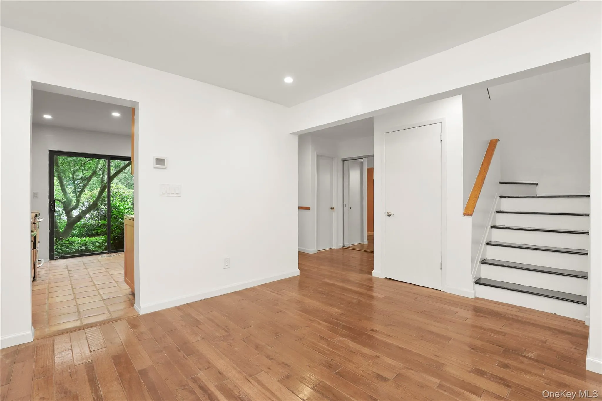 Empty room featuring light wood finished floors, stairway, recessed lighting, and baseboards Empty room featuring light wood finished floors, stairway, recessed lighting, and baseboards
