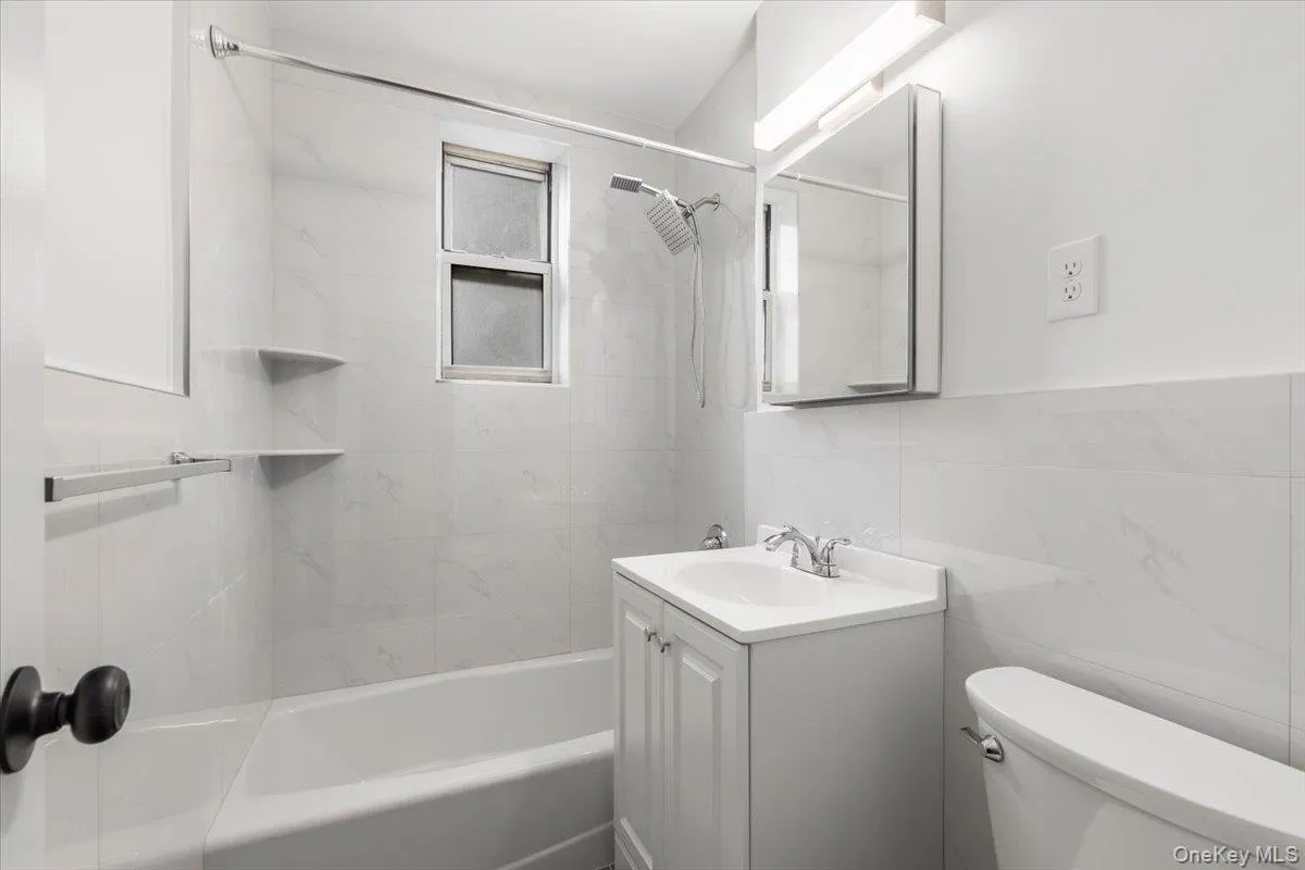 Bathroom featuring a white vanity with integrated sink, chrome faucet, and mirrored medicine cabinet Bathroom featuring a white vanity with integrated sink, chrome faucet, and mirrored medicine cabinet