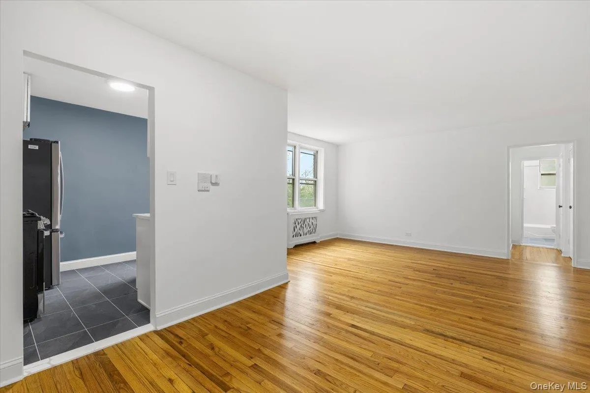 Open concept living area with natural wood-finish flooring, white walls, and a window providing natural light Open concept living area with natural wood-finish flooring, white walls, and a window providing natural light