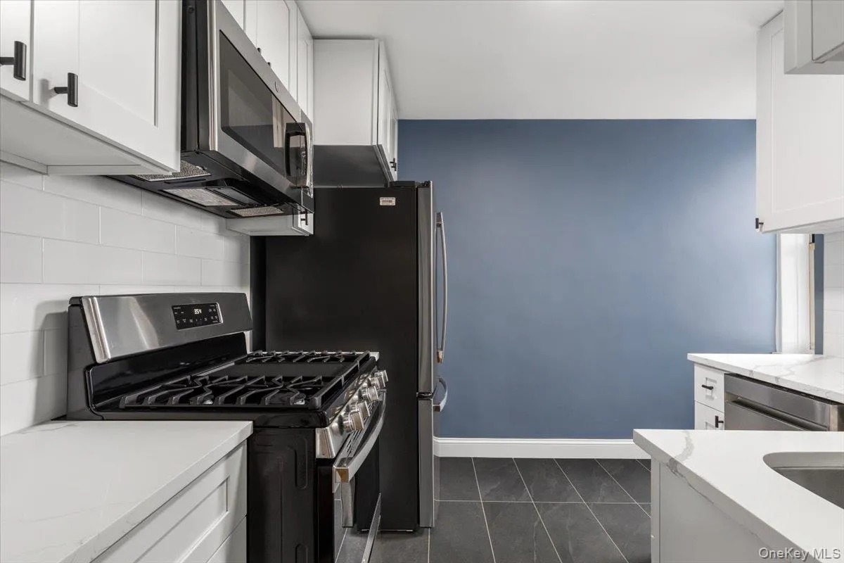 Modern kitchen featuring white shaker cabinetry, stainless steel appliances, white subway tile backsplash, and light-toned countertops Modern kitchen featuring white shaker cabinetry, stainless steel appliances, white subway tile backsplash, and light-toned countertops