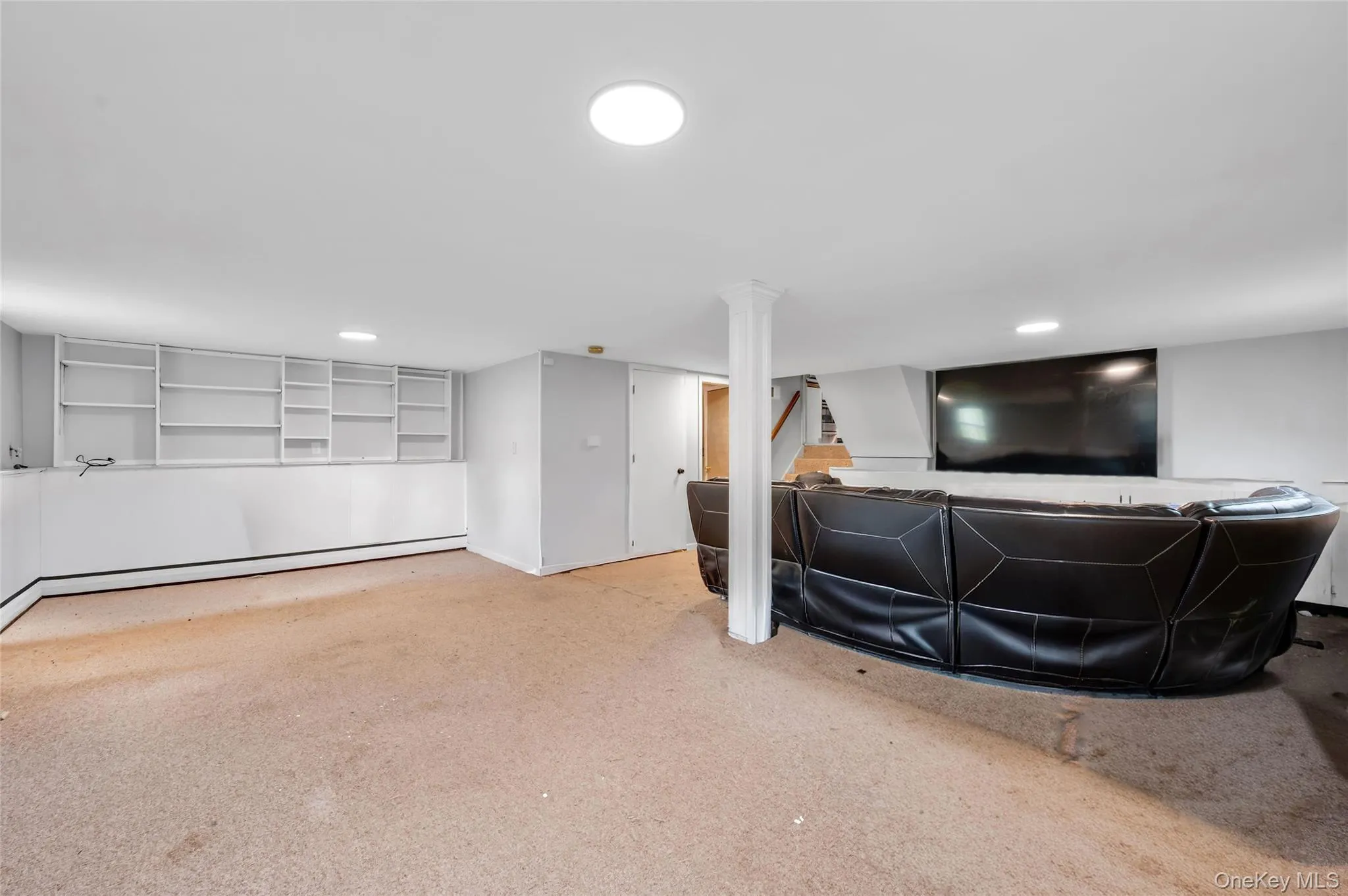 Expansive room featuring built-in shelving, carpet flooring, recessed lighting, and a white support column Expansive room featuring built-in shelving, carpet flooring, recessed lighting, and a white support column