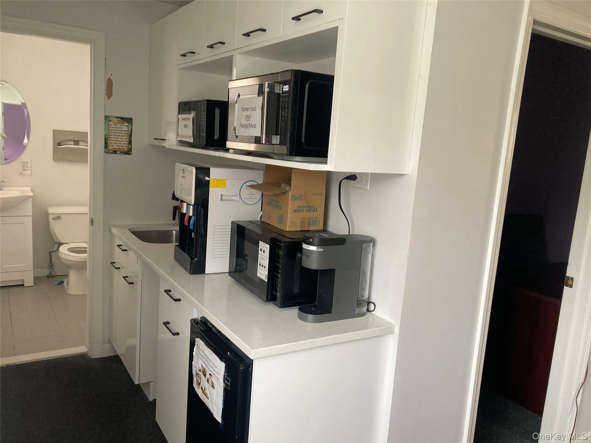 White cabinetry with black hardware, integrated countertop sink, and quartz-finish countertop White cabinetry with black hardware, integrated countertop sink, and quartz-finish countertop