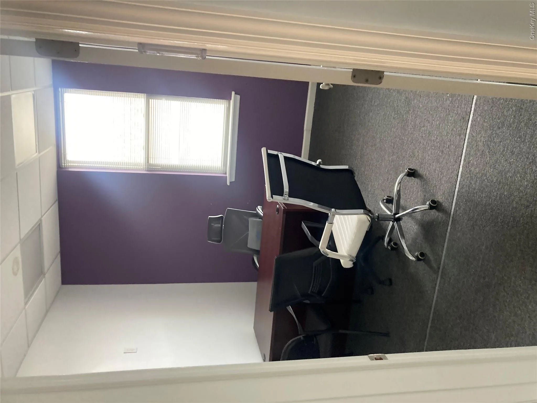 Office space featuring dark carpet flooring and a purple accent wall Office space featuring dark carpet flooring and a purple accent wall