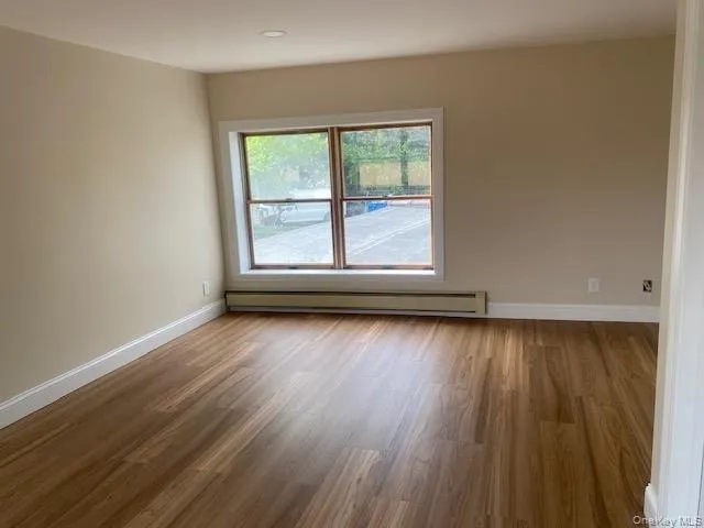 Spare room with a baseboard heating unit, wood finished floors, and baseboards Spare room with a baseboard heating unit, wood finished floors, and baseboards