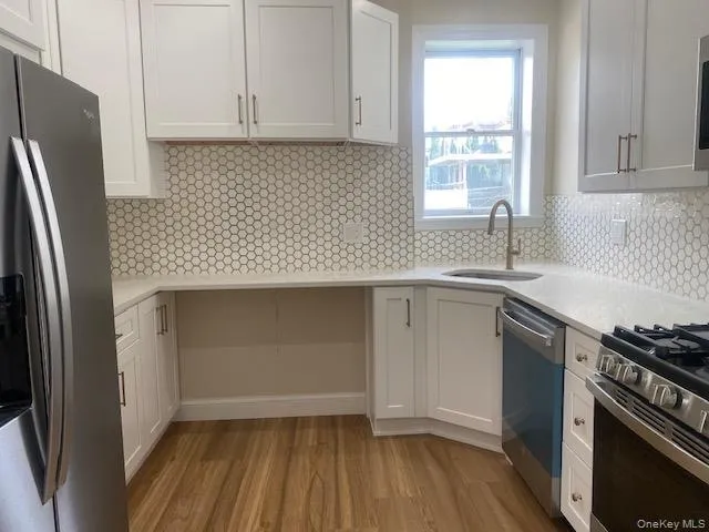 Kitchen with appliances with stainless steel finishes, a sink, light countertops, and light wood finished floors Kitchen with appliances with stainless steel finishes, a sink, light countertops, and light wood finished floors