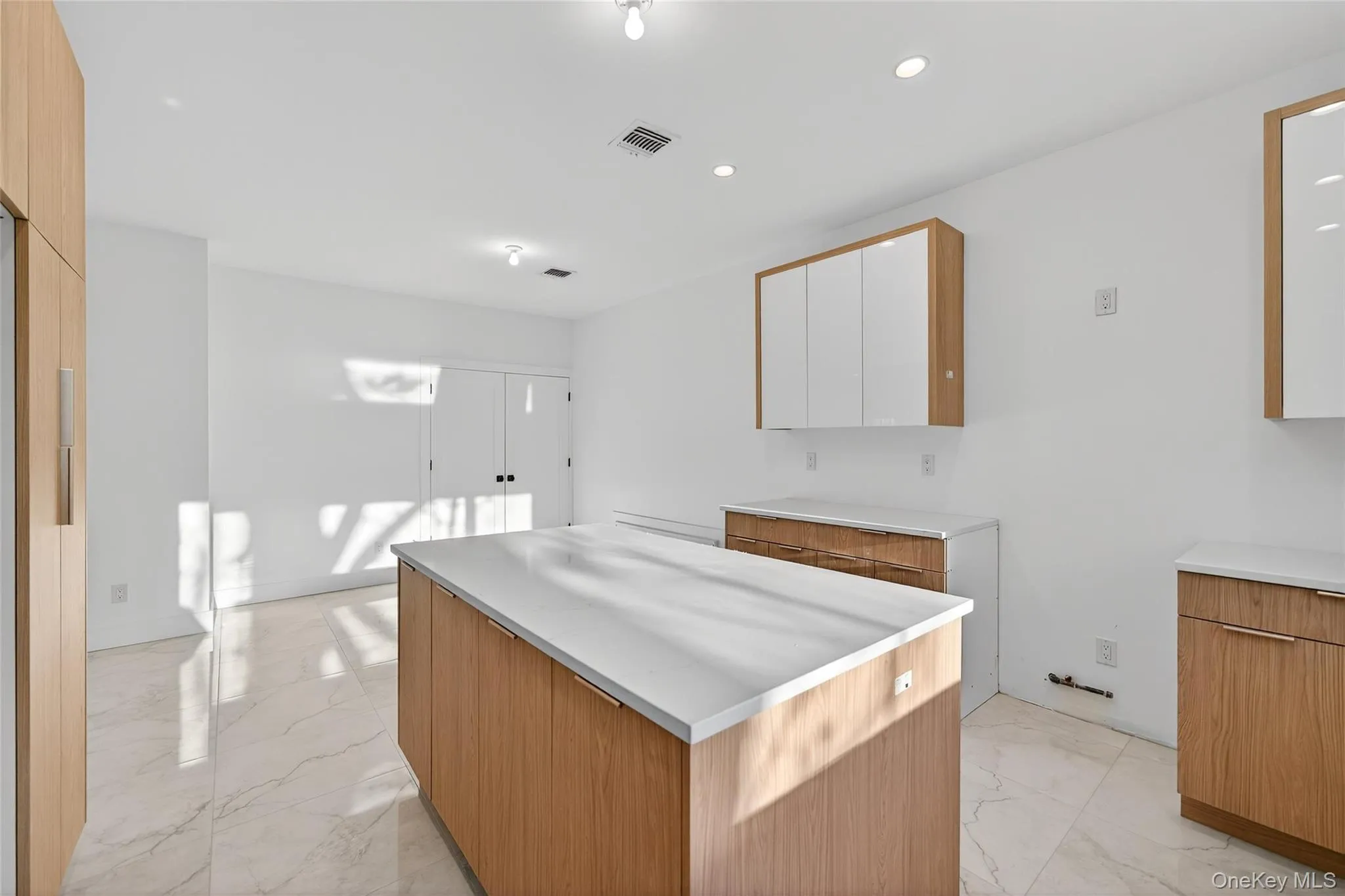 Kitchen featuring a center island, light marble finish floors, brown cabinetry, recessed lighting, and modern cabinets Kitchen featuring a center island, light marble finish floors, brown cabinetry, recessed lighting, and modern cabinets