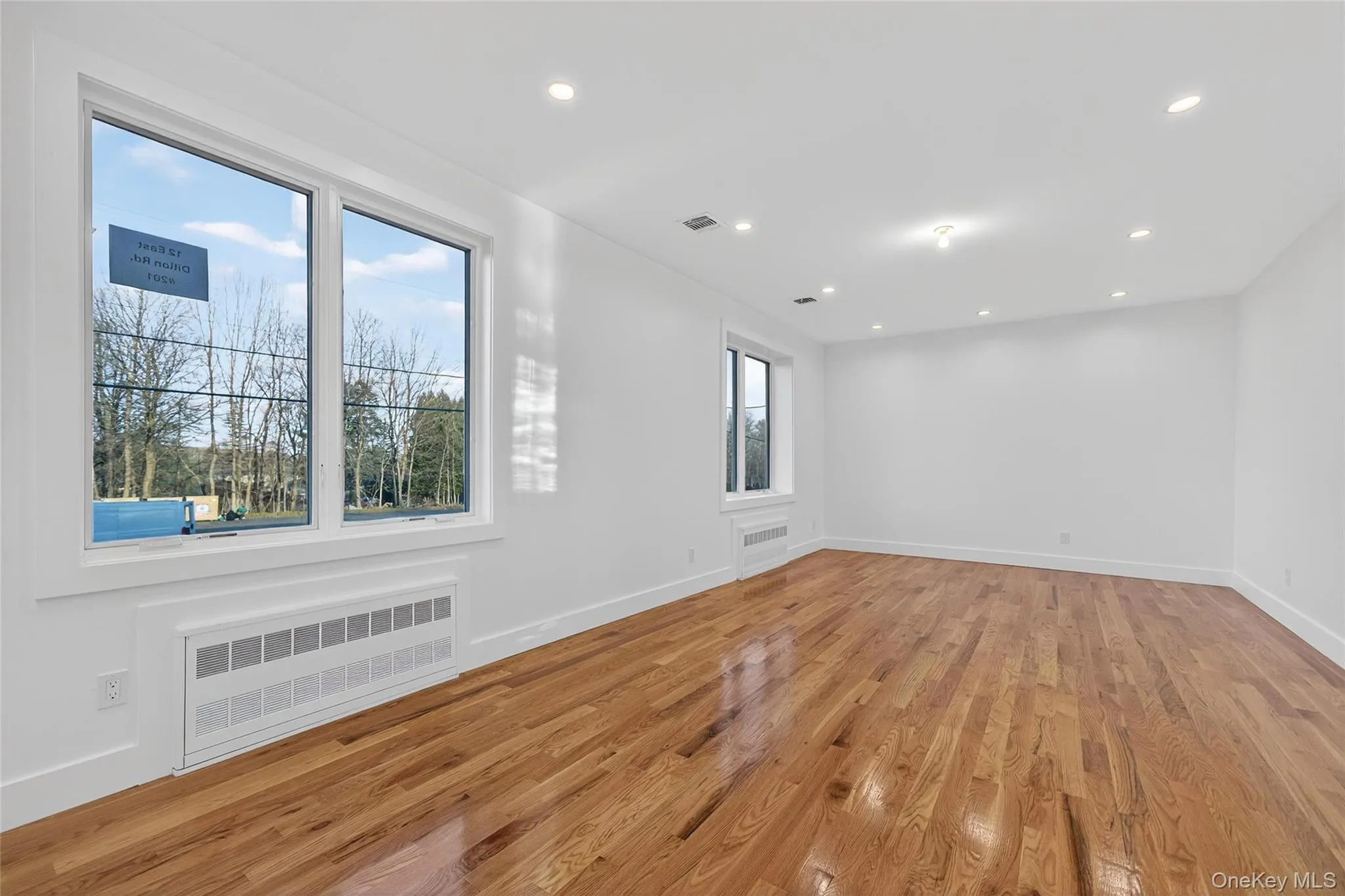 Empty room featuring radiator heating unit, light wood-style floors, and recessed lighting Empty room featuring radiator heating unit, light wood-style floors, and recessed lighting