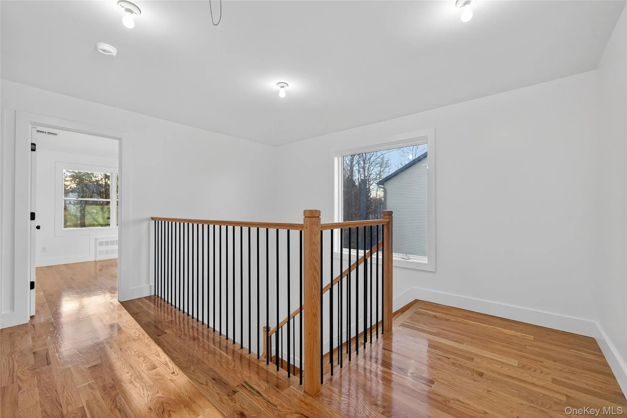 Hallway with light wood-style flooring, an upstairs landing, and plenty of natural light Hallway with light wood-style flooring, an upstairs landing, and plenty of natural light