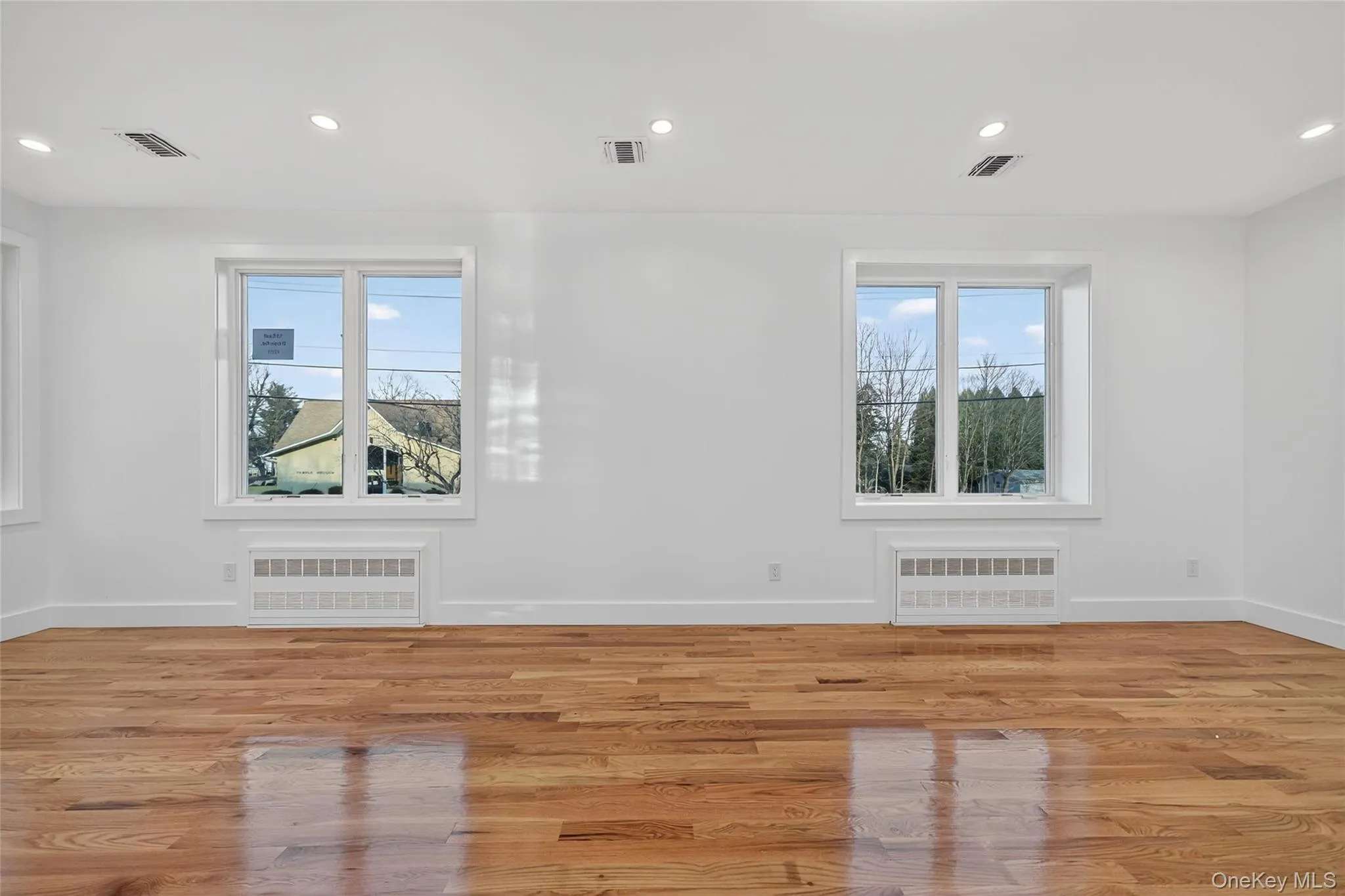 Empty room with recessed lighting, light wood-style floors, and radiator heating unit Empty room with recessed lighting, light wood-style floors, and radiator heating unit