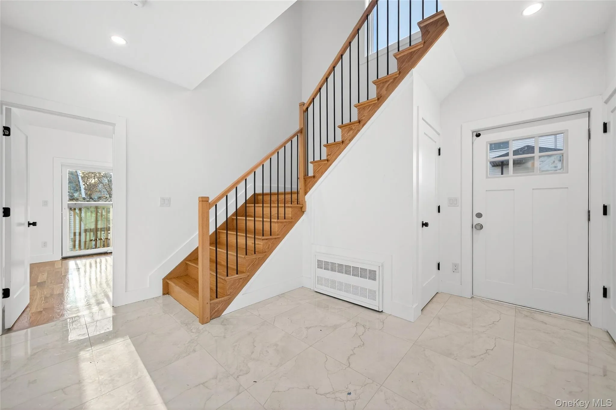Entrance foyer featuring light marble finish flooring, recessed lighting, stairs, and radiator Entrance foyer featuring light marble finish flooring, recessed lighting, stairs, and radiator