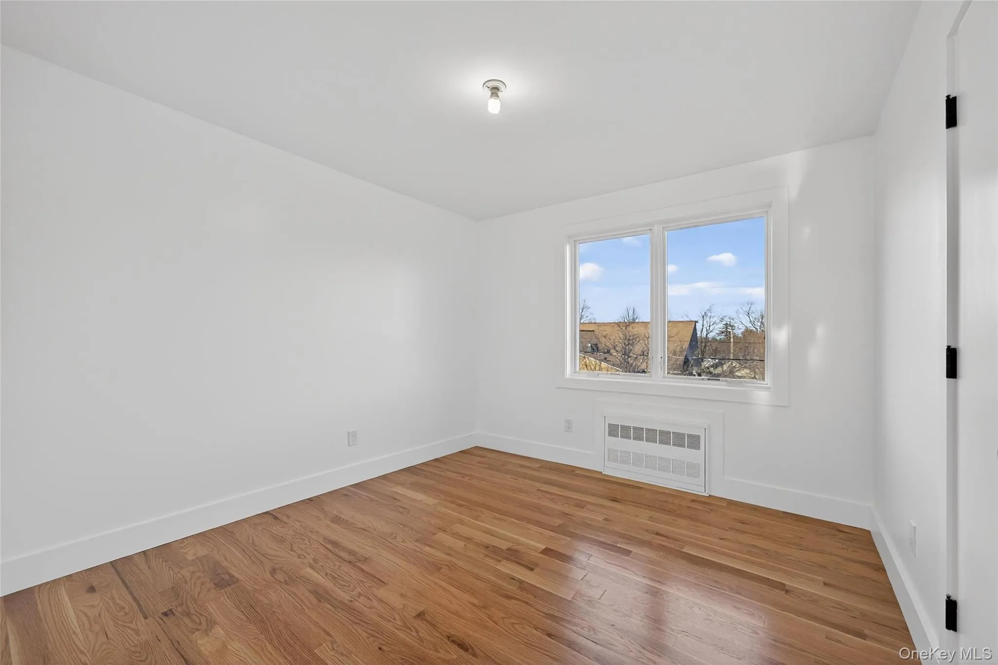 Empty room featuring wood finished floors and radiator Empty room featuring wood finished floors and radiator