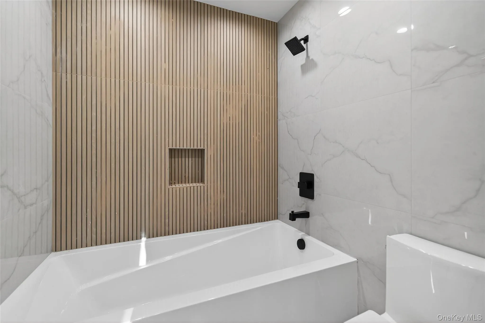 Bathroom with tile walls, shower / bathtub combination, and stone wall Bathroom with tile walls, shower / bathtub combination, and stone wall