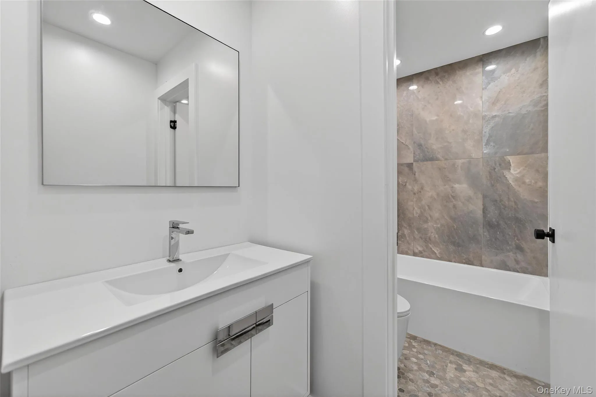 Bathroom featuring vanity, recessed lighting, stone finish flooring, and washtub / shower combination Bathroom featuring vanity, recessed lighting, stone finish flooring, and washtub / shower combination