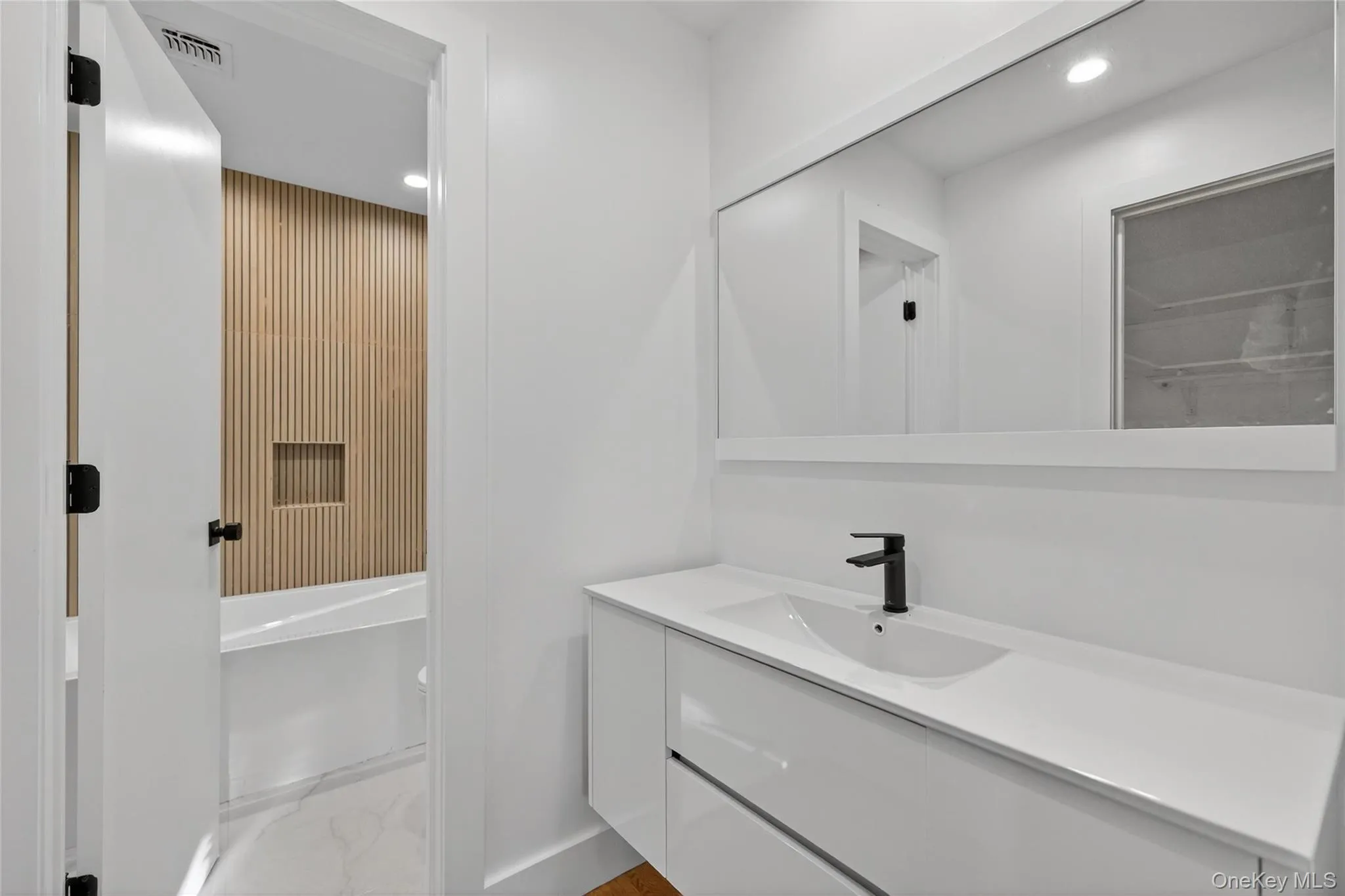 Bathroom with vanity, recessed lighting, a tub to relax in, and light marble finish floors Bathroom with vanity, recessed lighting, a tub to relax in, and light marble finish floors