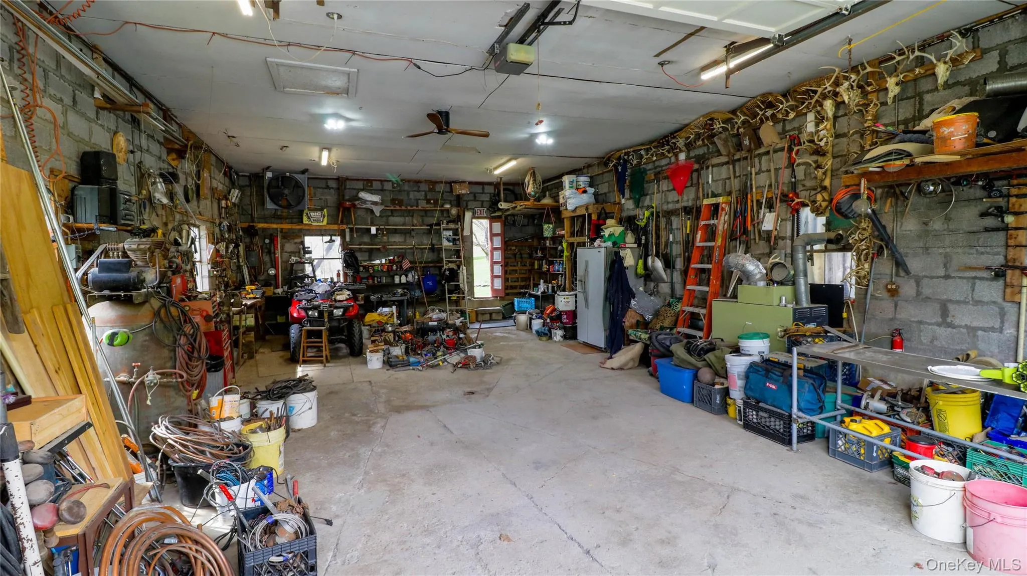 Spacious garage featuring concrete block walls, a concrete floor, and multiple windows Spacious garage featuring concrete block walls, a concrete floor, and multiple windows