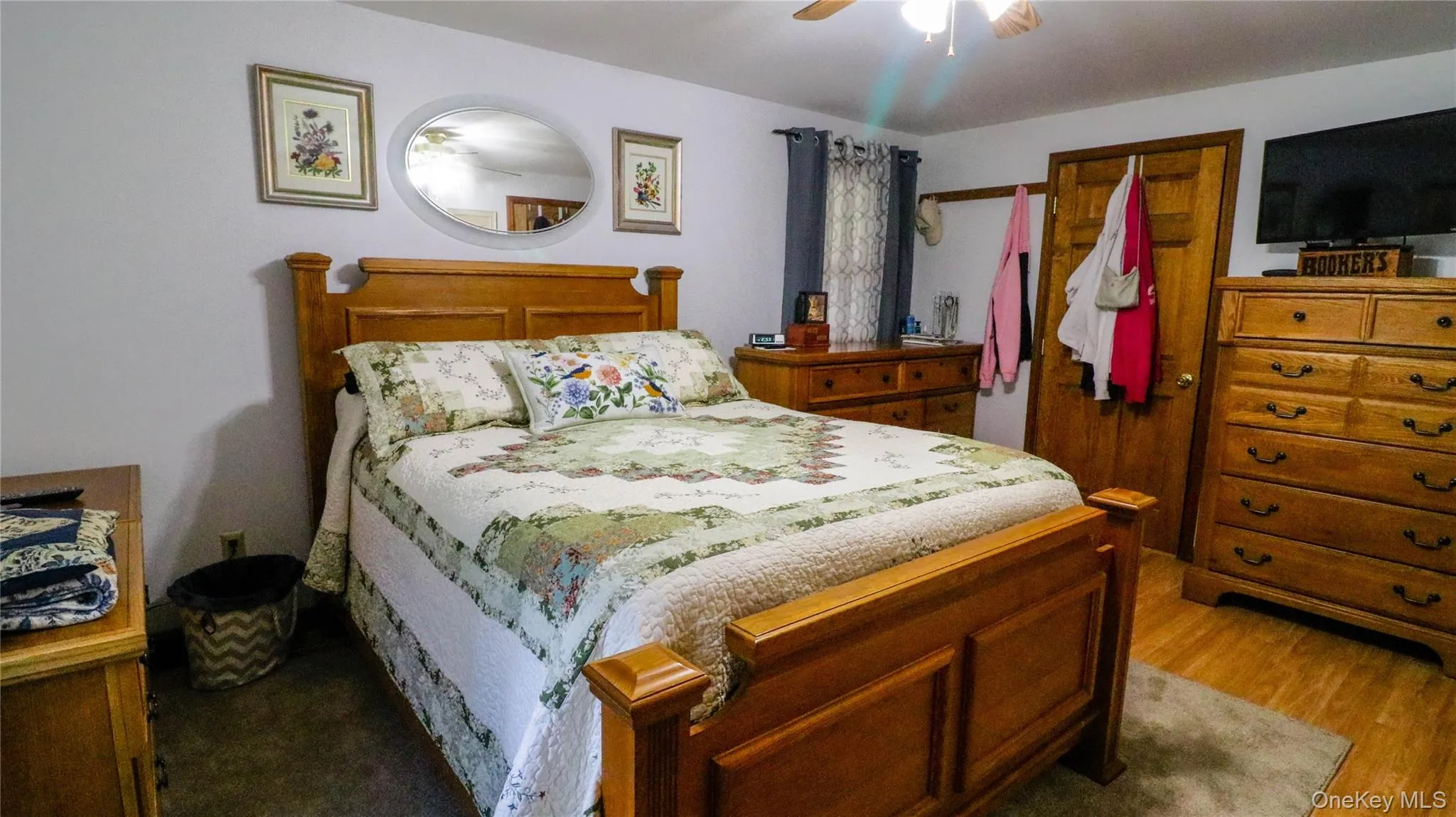 Bedroom featuring wood-finish flooring, a ceiling fan with integrated lighting, and a solid wood door Bedroom featuring wood-finish flooring, a ceiling fan with integrated lighting, and a solid wood door