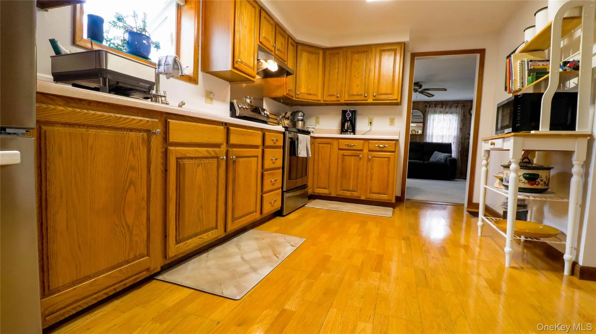 Kitchen featuring wood-finish flooring, ample cabinetry with light wood finishes, and a light-toned countertop Kitchen featuring wood-finish flooring, ample cabinetry with light wood finishes, and a light-toned countertop
