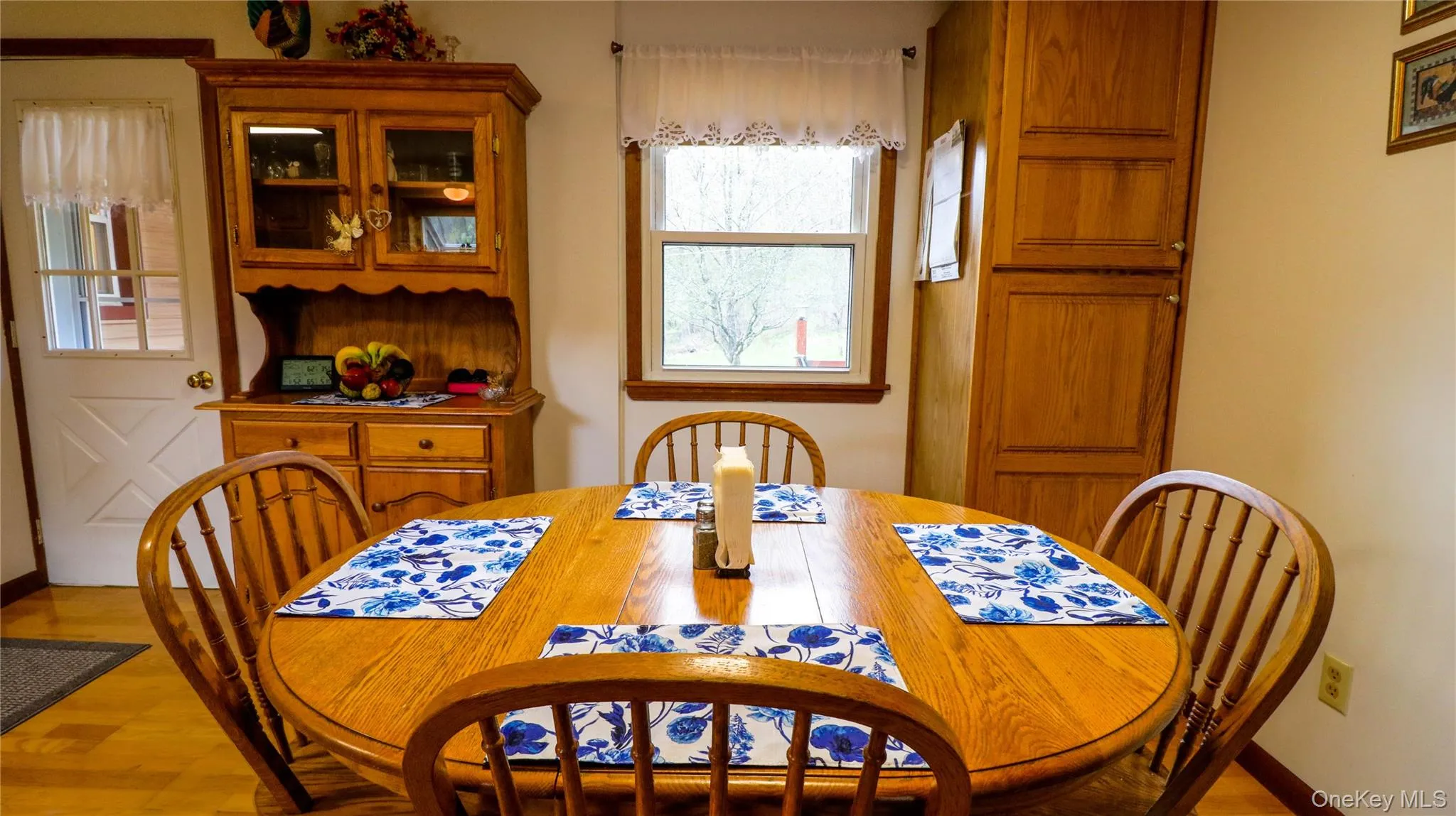 Dining area with wood-finish flooring, a window offering natural light, and built-in wood cabinetry for storage Dining area with wood-finish flooring, a window offering natural light, and built-in wood cabinetry for storage