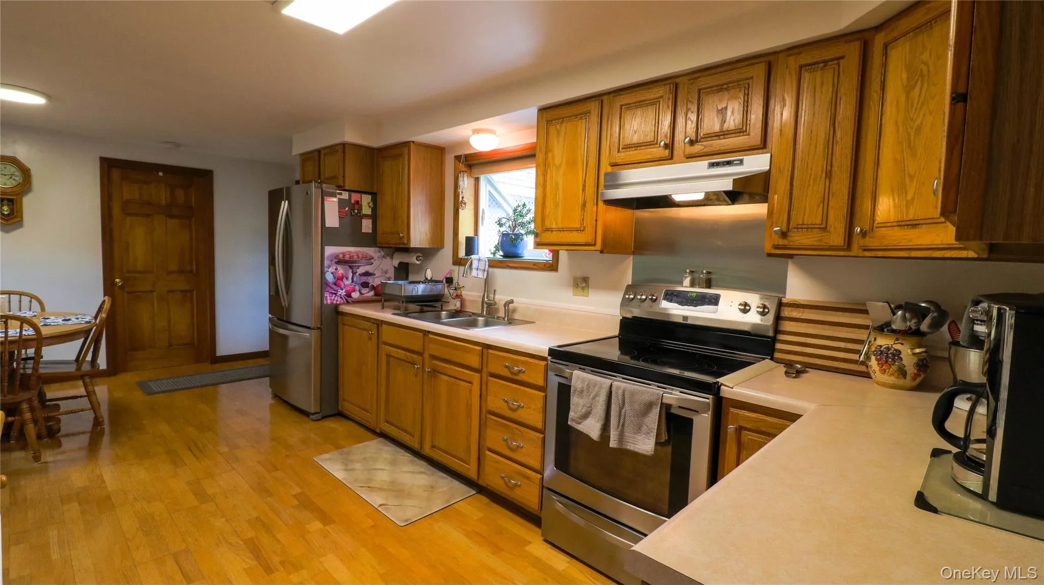 Kitchen featuring wood-finish flooring, ample wood cabinetry, and stainless steel appliances including a refrigerator and range Kitchen featuring wood-finish flooring, ample wood cabinetry, and stainless steel appliances including a refrigerator and range