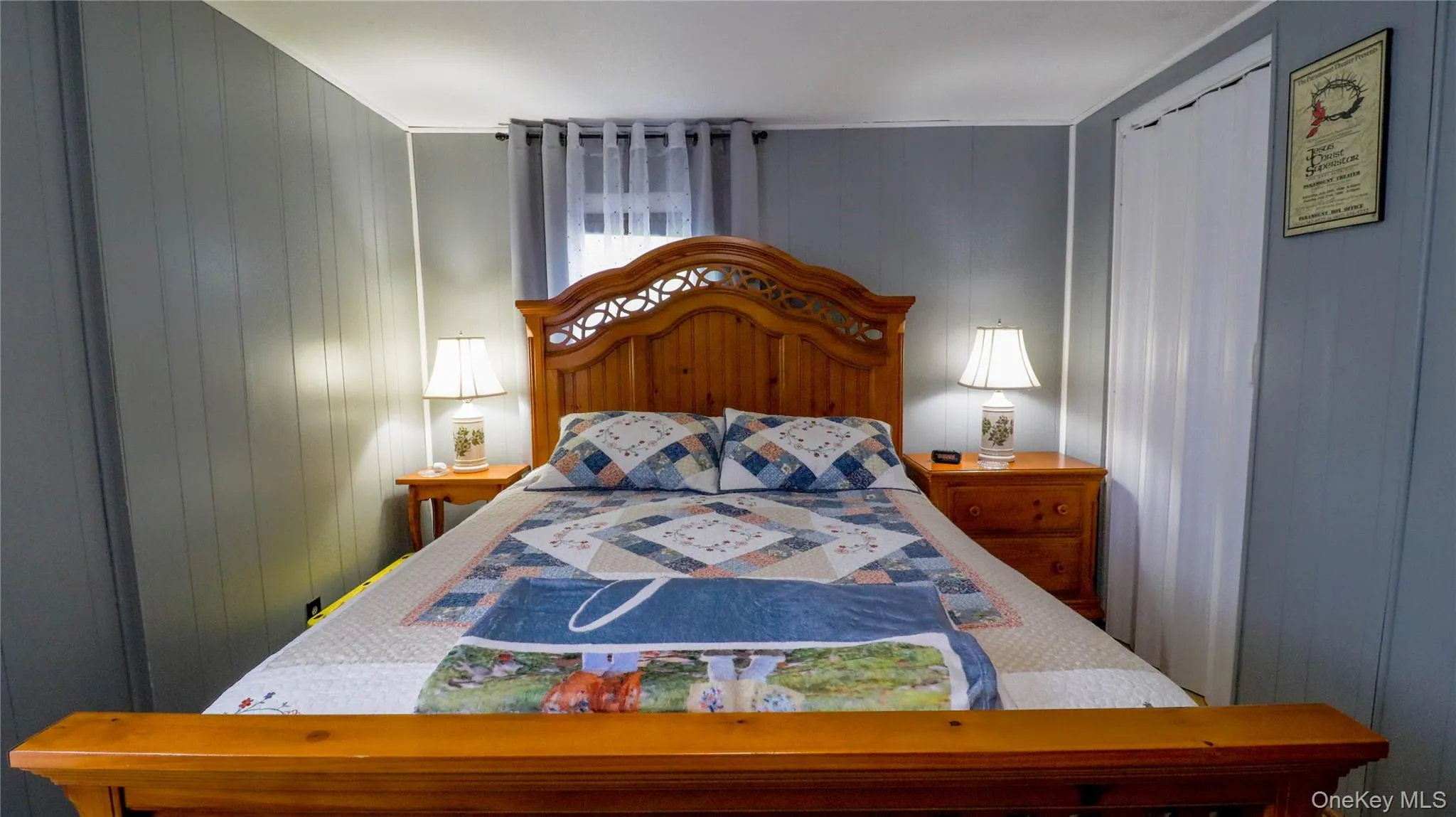 Bedroom featuring board and batten wall treatment, window with sheer and blackout curtains, and a built-in recessed closet with privacy curtain Bedroom featuring board and batten wall treatment, window with sheer and blackout curtains, and a built-in recessed closet with privacy curtain