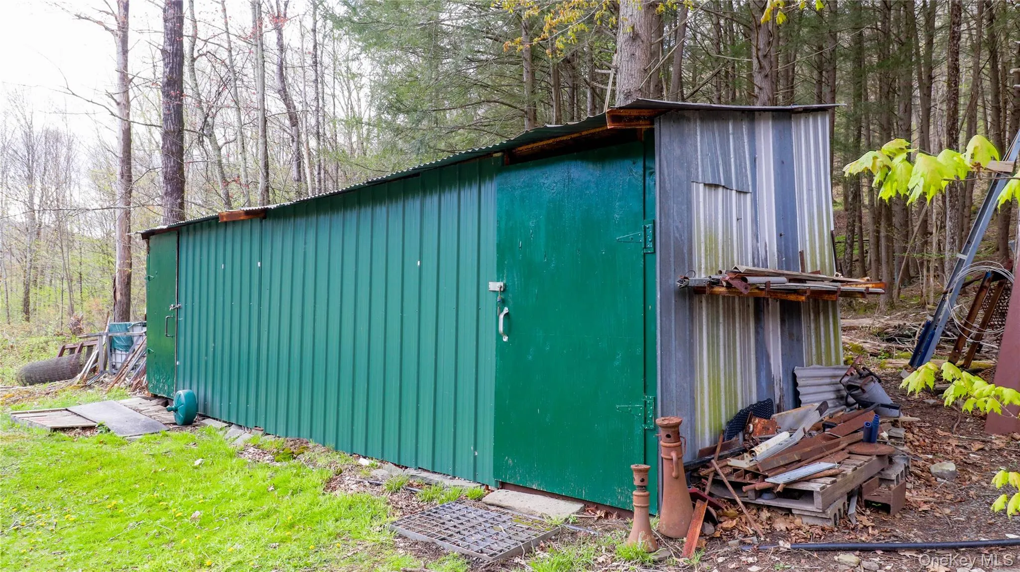 Long metal storage shed with a corrugated green facade and a galvanized steel side panel Long metal storage shed with a corrugated green facade and a galvanized steel side panel