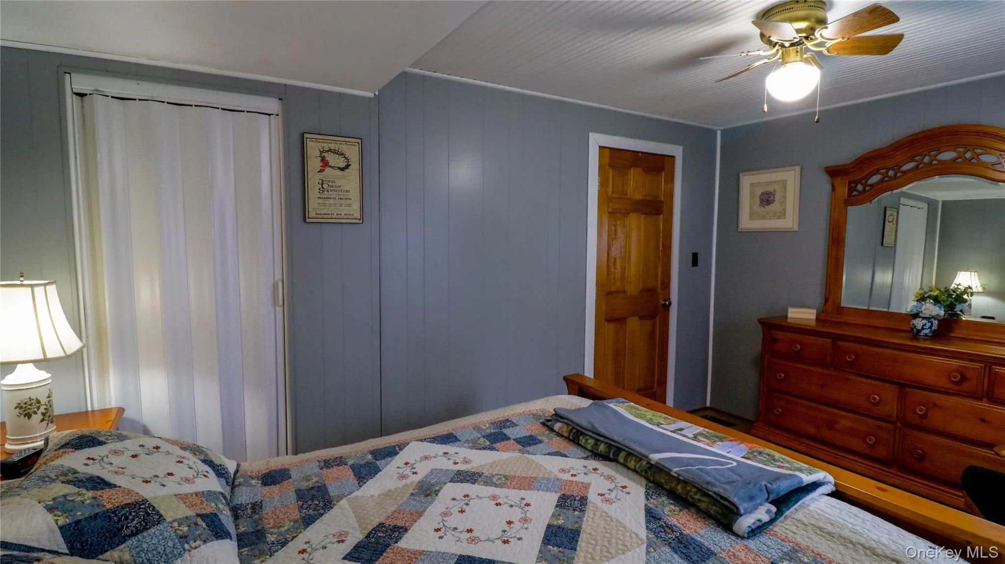 Room featuring light gray wall paneling, a wood-finish door, and a white beadboard ceiling Room featuring light gray wall paneling, a wood-finish door, and a white beadboard ceiling
