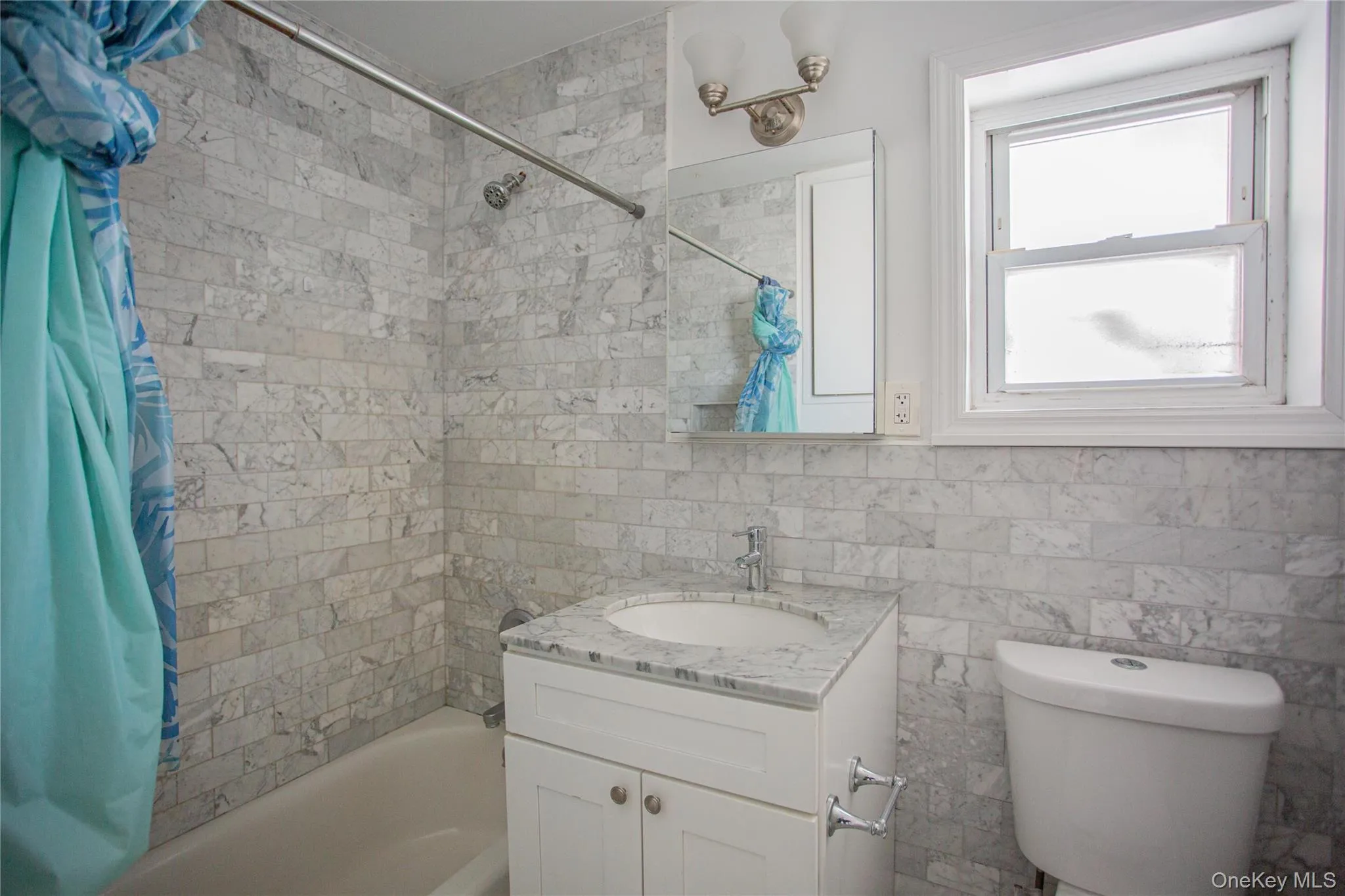 Full bathroom featuring shower / bathtub combination with curtain, vanity, and tile walls Full bathroom featuring shower / bathtub combination with curtain, vanity, and tile walls