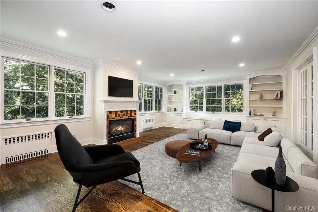 Opening off the kitchen, this large family room features hardwood floors, built-in cabinetry and shelving and a wood-burning fireplace. Digitally staged. Opening off the kitchen, this large family room features hardwood floors, built-in cabinetry and shelving and a wood-burning fireplace. Digitally staged.