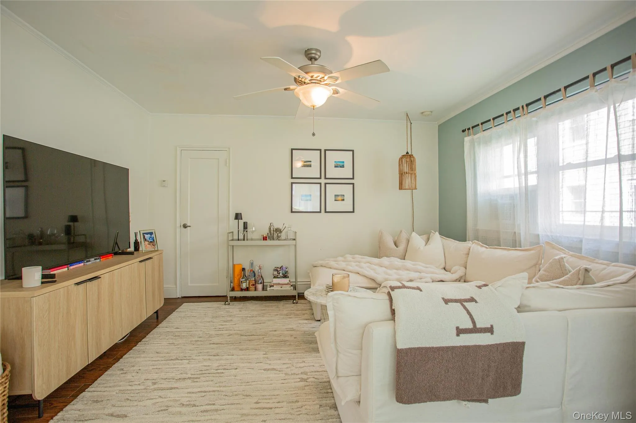 Living room with a ceiling fan, crown molding, and wood finished floors Living room with a ceiling fan, crown molding, and wood finished floors