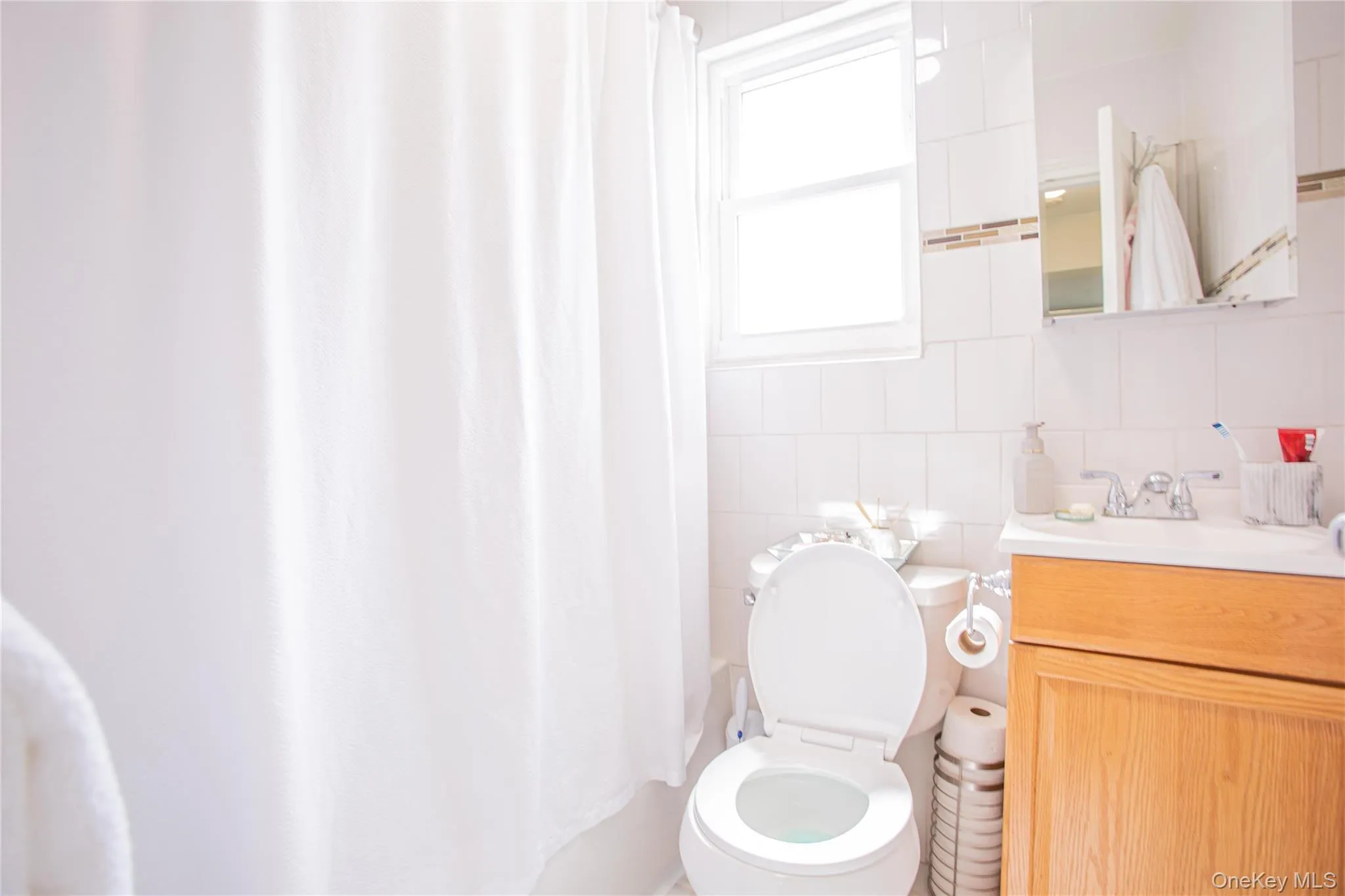 Bathroom featuring vanity, toilet, and shower / bath combo with shower curtain Bathroom featuring vanity, toilet, and shower / bath combo with shower curtain