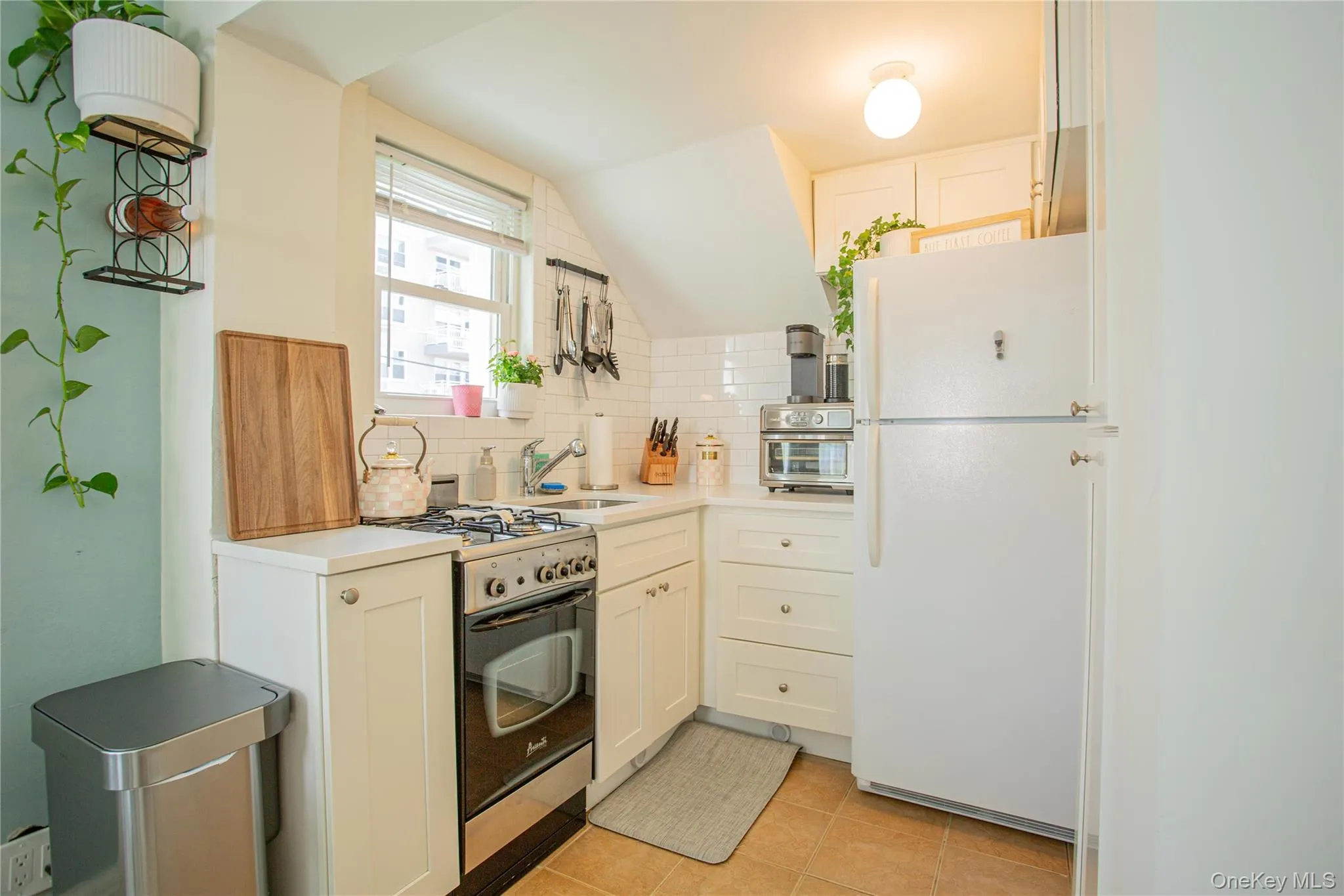Kitchen with freestanding refrigerator, gas range, tasteful backsplash, light countertops, and a sink Kitchen with freestanding refrigerator, gas range, tasteful backsplash, light countertops, and a sink