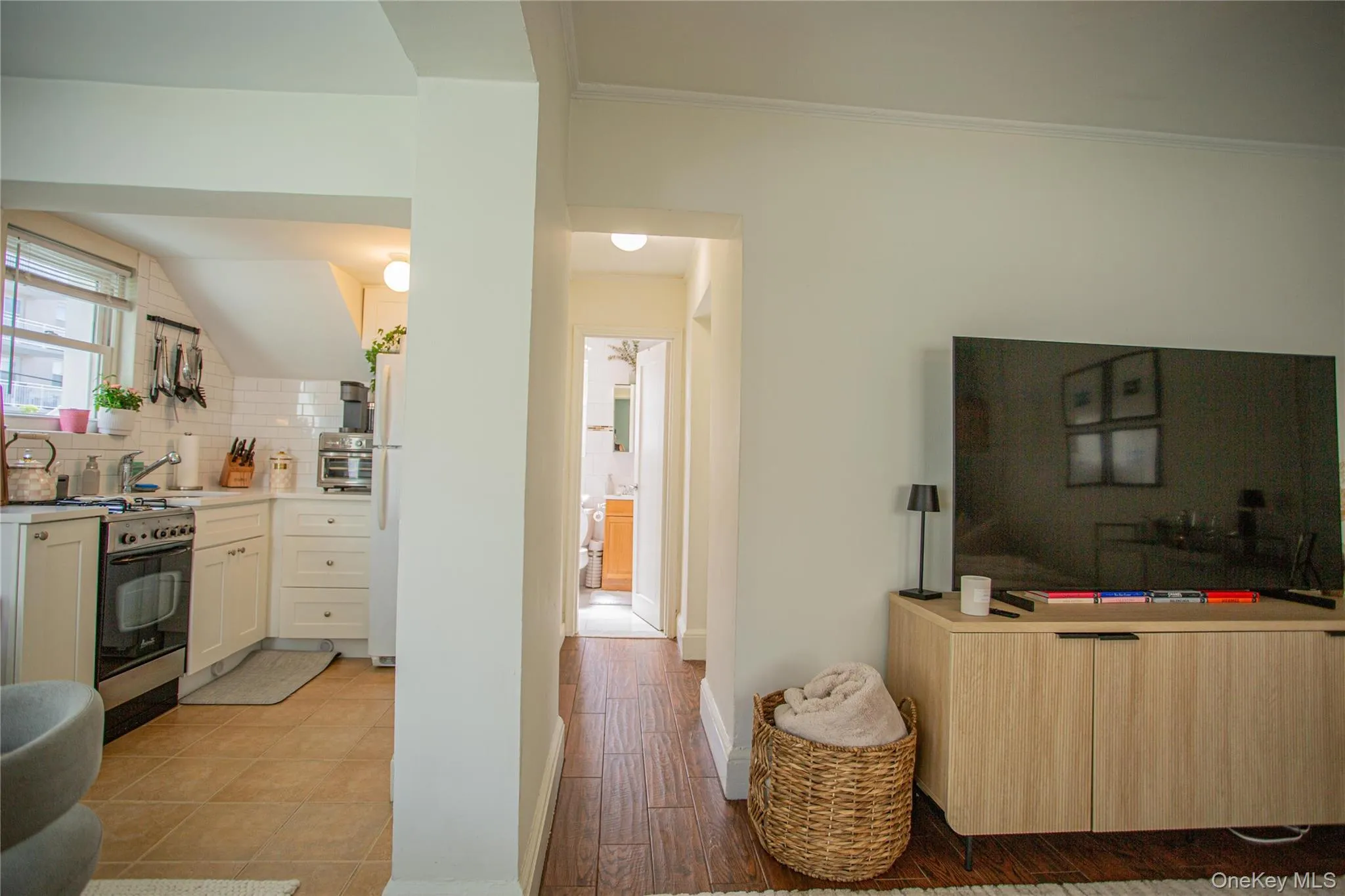 Kitchen featuring range with gas stovetop, decorative backsplash, ornamental molding, light countertops, and freestanding refrigerator Kitchen featuring range with gas stovetop, decorative backsplash, ornamental molding, light countertops, and freestanding refrigerator