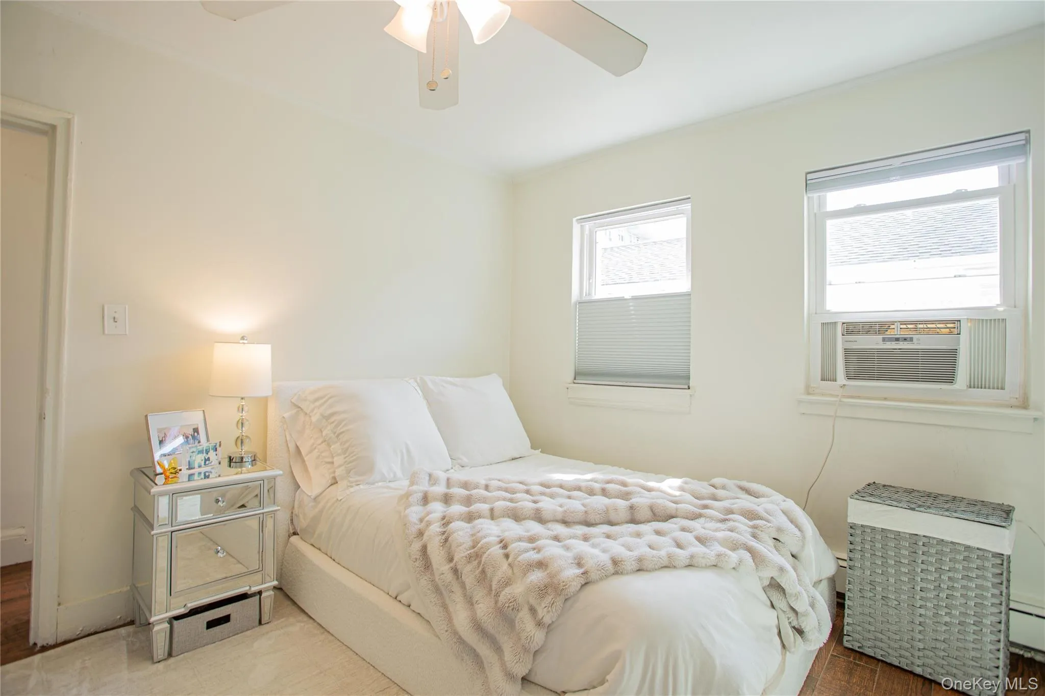 Bedroom featuring cooling unit, wood finished floors, ornamental molding, baseboard heating, and a ceiling fan Bedroom featuring cooling unit, wood finished floors, ornamental molding, baseboard heating, and a ceiling fan