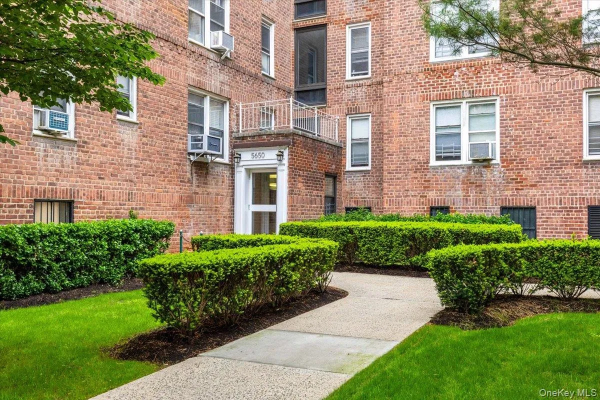 Brick exterior building with well-maintained shrubbery and a concrete pathway leading to the main entrance Brick exterior building with well-maintained shrubbery and a concrete pathway leading to the main entrance