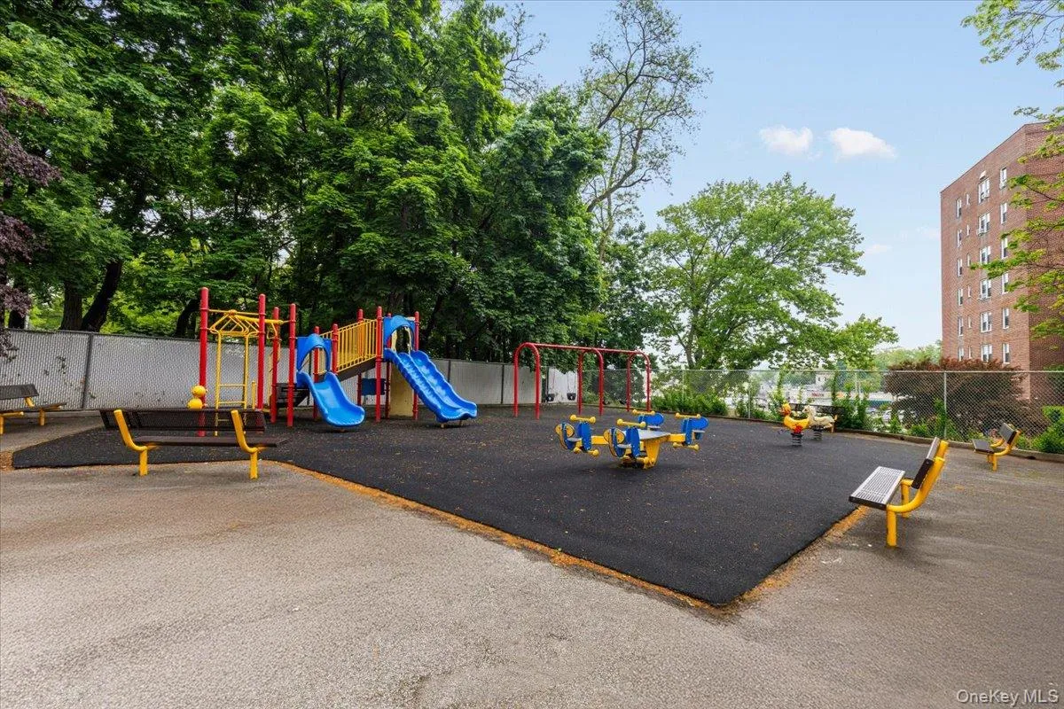 Expansive outdoor play area featuring a soft rubberized surface, multiple slides, swing sets, and spring riders Expansive outdoor play area featuring a soft rubberized surface, multiple slides, swing sets, and spring riders