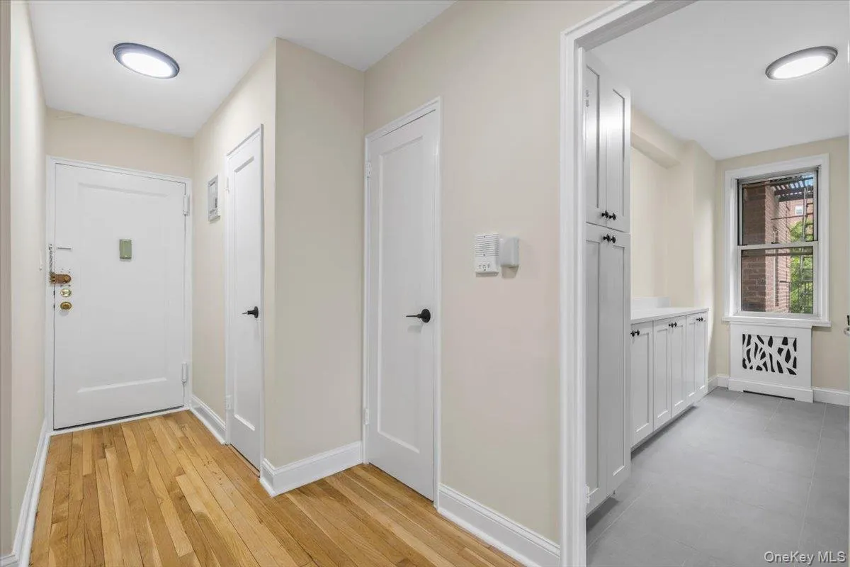 Entryway featuring wood-finish flooring, two panel doors with matte black hardware, and overhead lighting Entryway featuring wood-finish flooring, two panel doors with matte black hardware, and overhead lighting