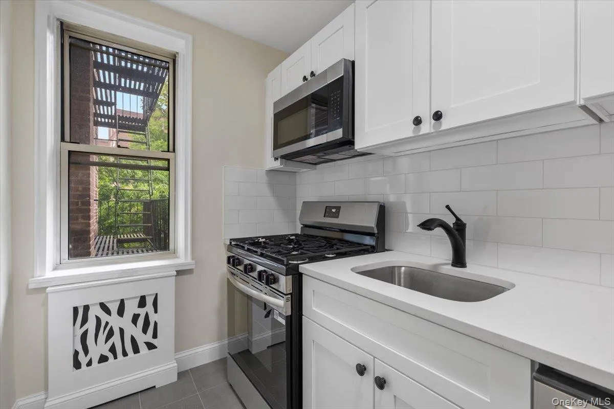 Modern kitchen featuring white shaker cabinetry, stainless steel appliances, a gas range, white subway tile backsplash, and light countertops Modern kitchen featuring white shaker cabinetry, stainless steel appliances, a gas range, white subway tile backsplash, and light countertops
