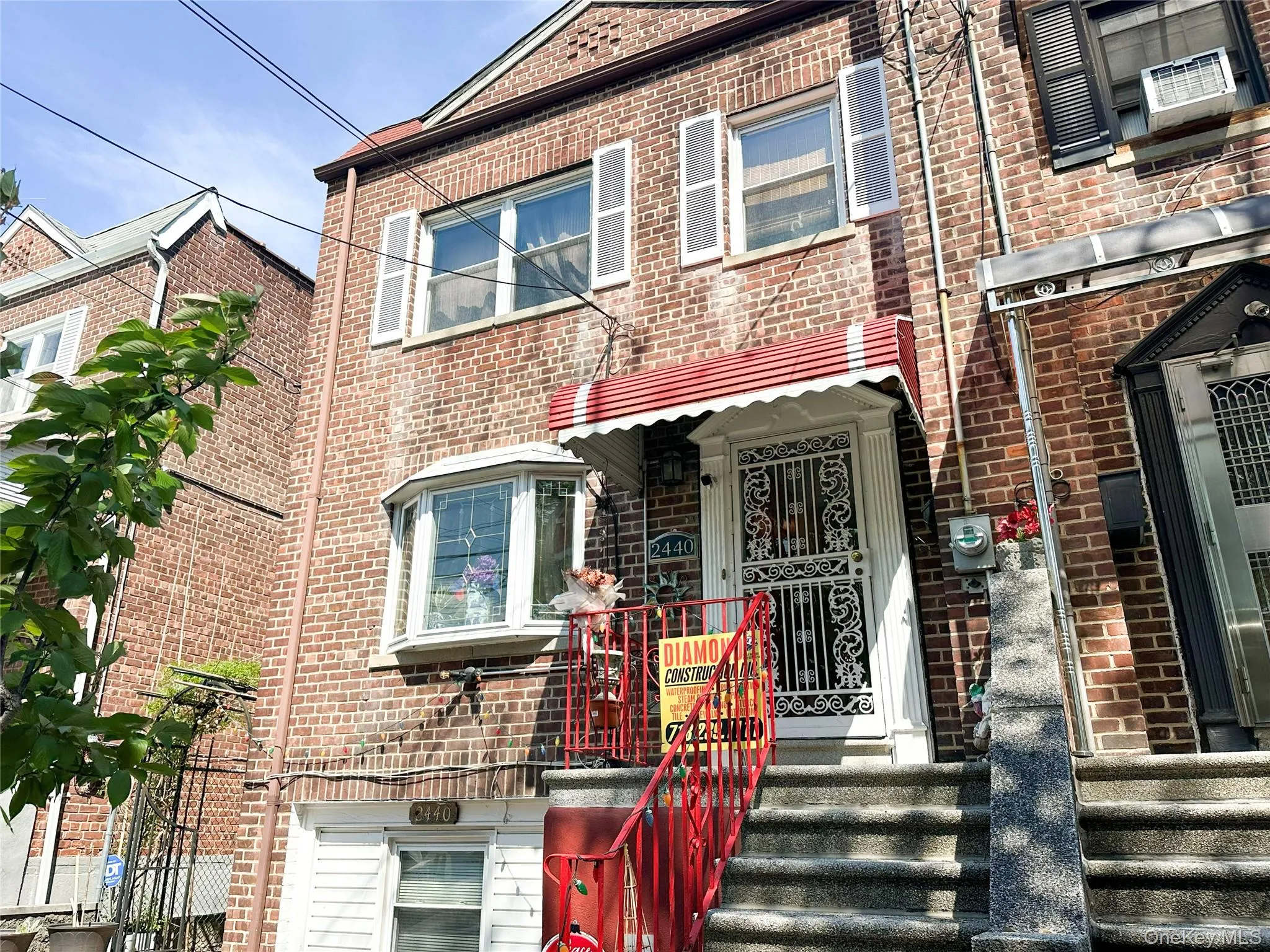 Brick facade townhouse with a second-story bay window, white louvered shutters, and a red awning over the entry Brick facade townhouse with a second-story bay window, white louvered shutters, and a red awning over the entry