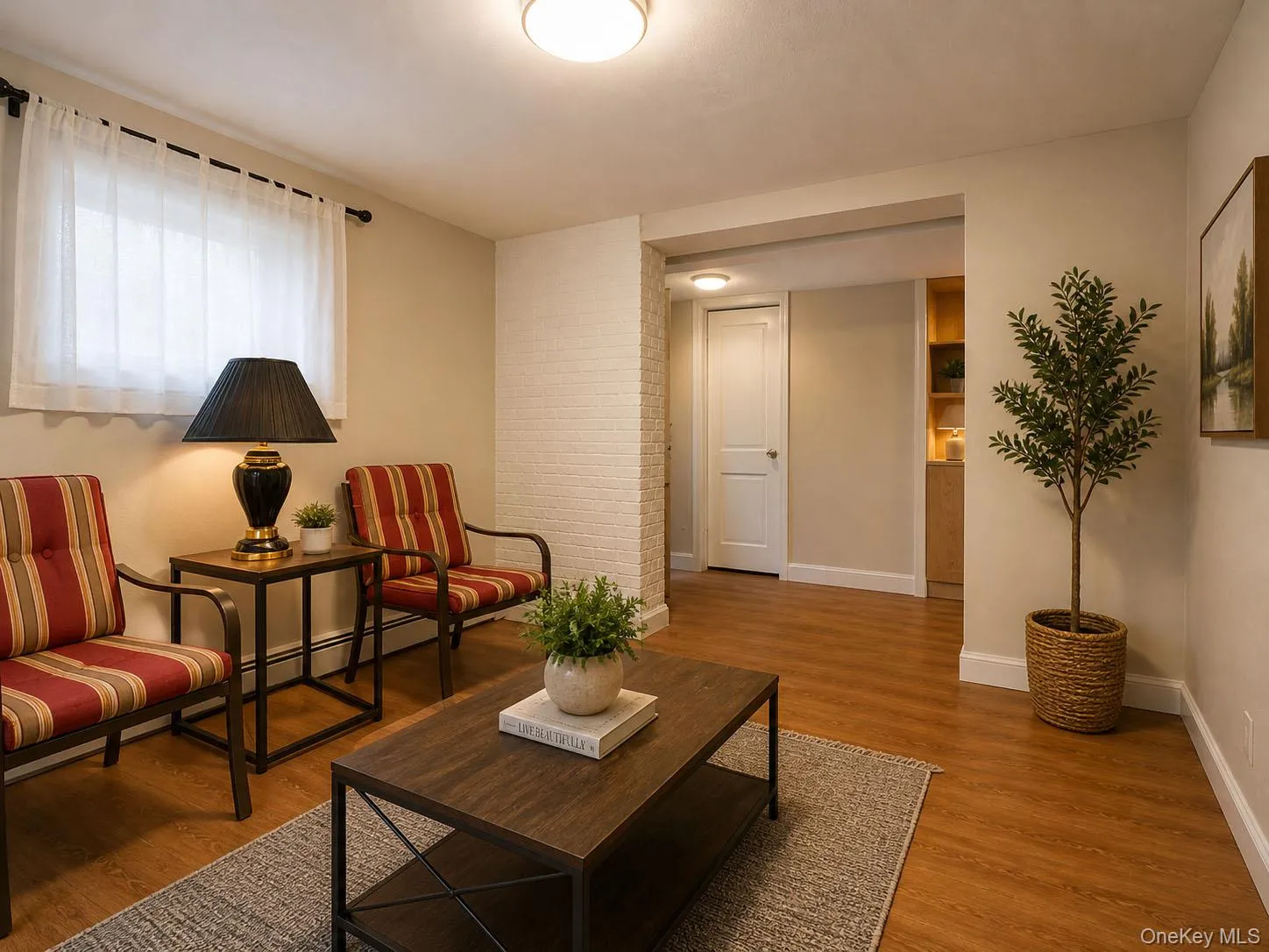 Bonus area featuring wood-laminate-finish flooring, a white brick accent wall, and a recessed doorway Bonus area featuring wood-laminate-finish flooring, a white brick accent wall, and a recessed doorway