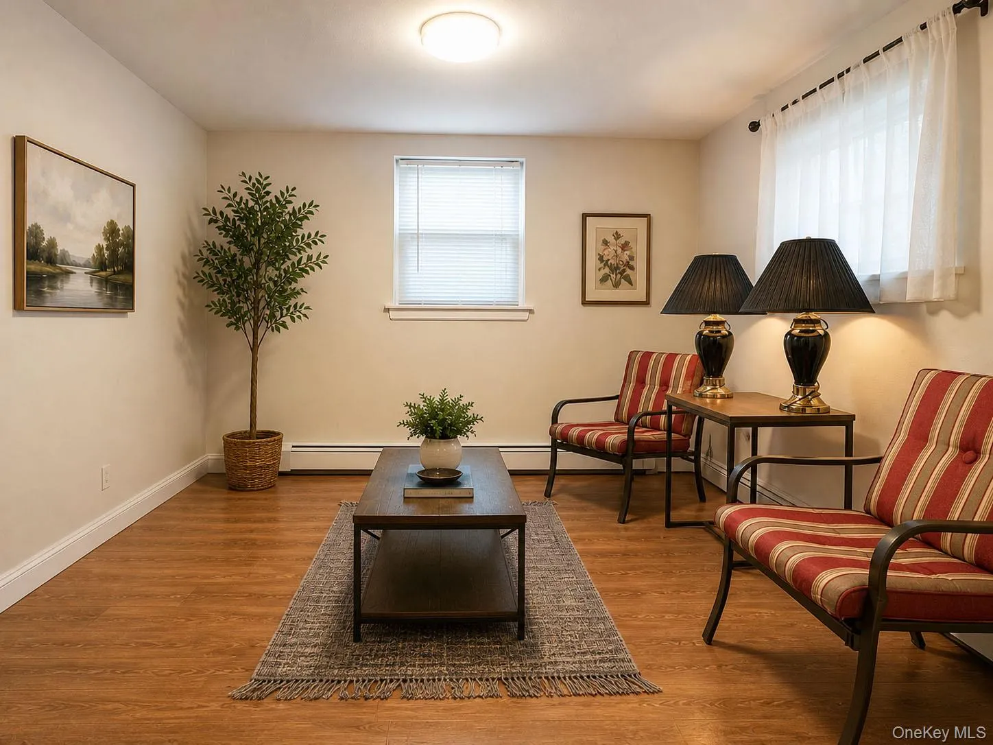 Spacious room featuring wood-laminate-finish flooring, neutral wall tones, baseboard trim, and multiple windows with blinds Spacious room featuring wood-laminate-finish flooring, neutral wall tones, baseboard trim, and multiple windows with blinds
