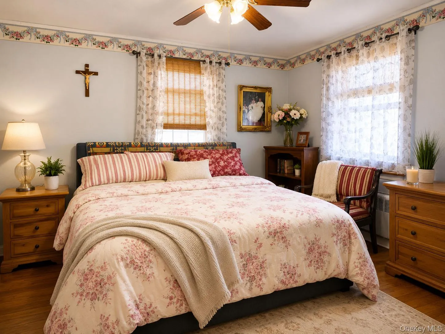 Bedroom featuring wood-finish flooring, two windows with woven wood shades, and a ceiling fan with integrated lighting Bedroom featuring wood-finish flooring, two windows with woven wood shades, and a ceiling fan with integrated lighting