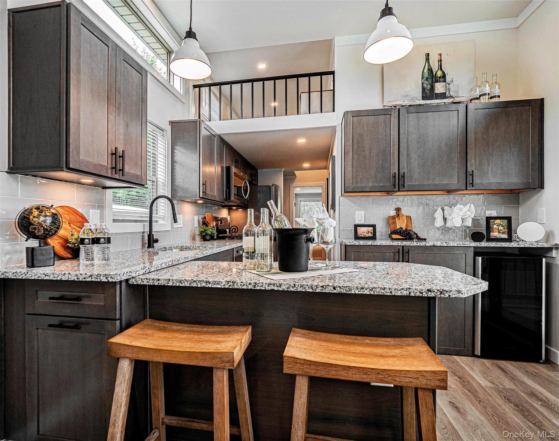 Kitchen with tasteful backsplash, dark brown cabinetry, wine cooler, light stone countertops, and recessed lighting Kitchen with tasteful backsplash, dark brown cabinetry, wine cooler, light stone countertops, and recessed lighting