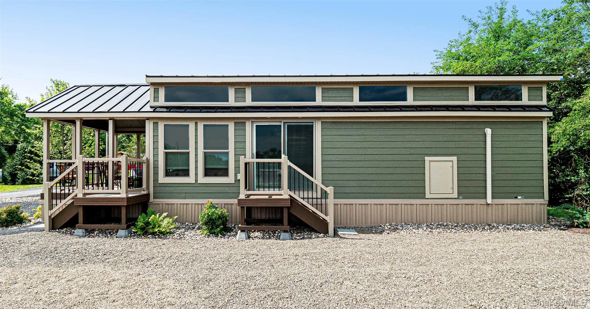 View of side with a metal roof, a porch, and a wooden deck View of side with a metal roof, a porch, and a wooden deck