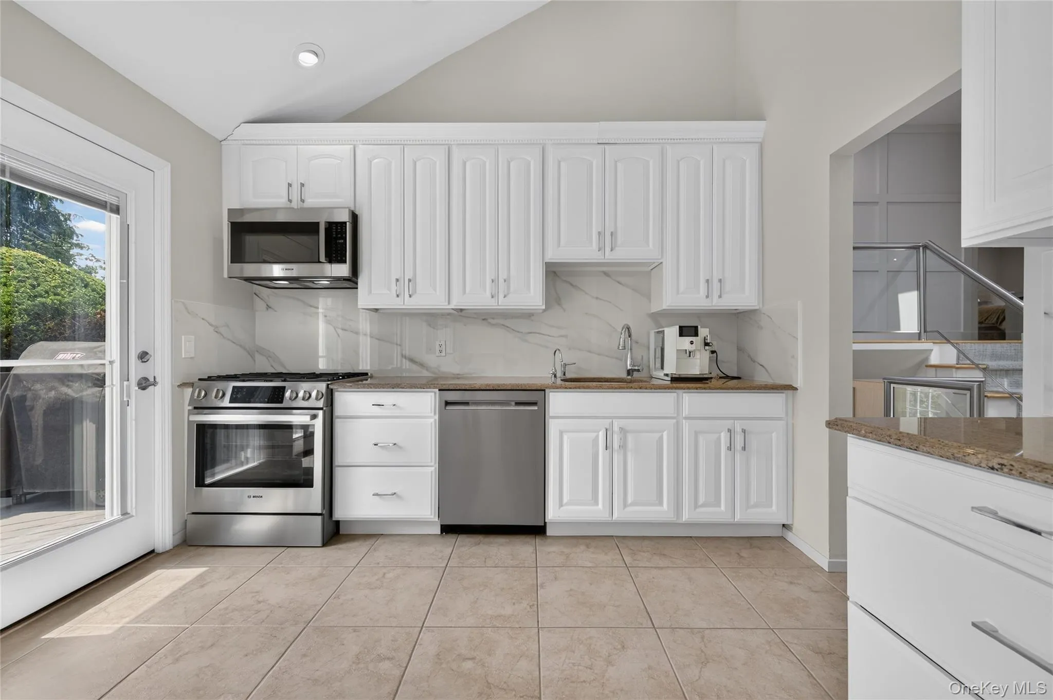 Kitchen featuring GAS stove, white cabinetry, stainless steel appliances, natural granite countertops, and tile flooring Kitchen featuring GAS stove, white cabinetry, stainless steel appliances, natural granite countertops, and tile flooring